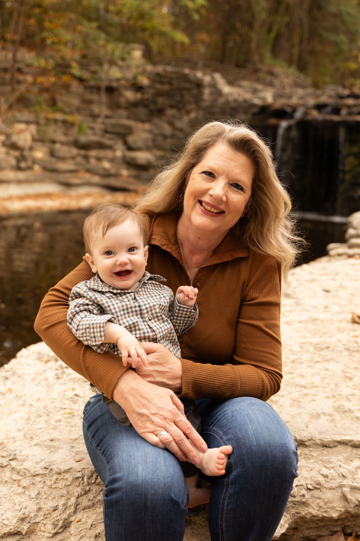 A heartwarming moment captured by a waterfall on a rocky outcrop.