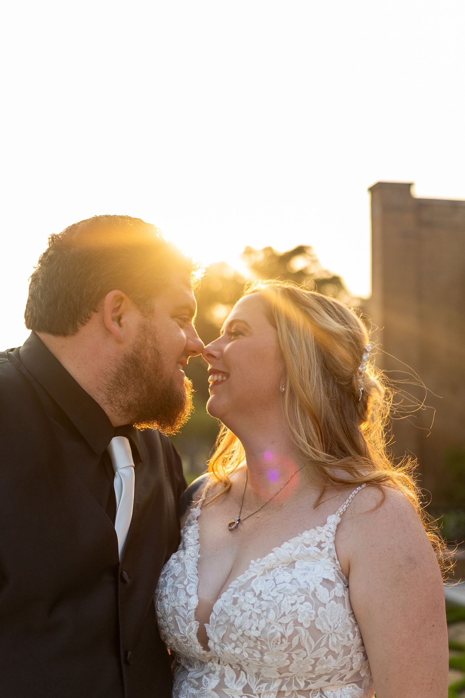A romantic sunset portrait of newlyweds sharing an intimate moment with golden backlighting.