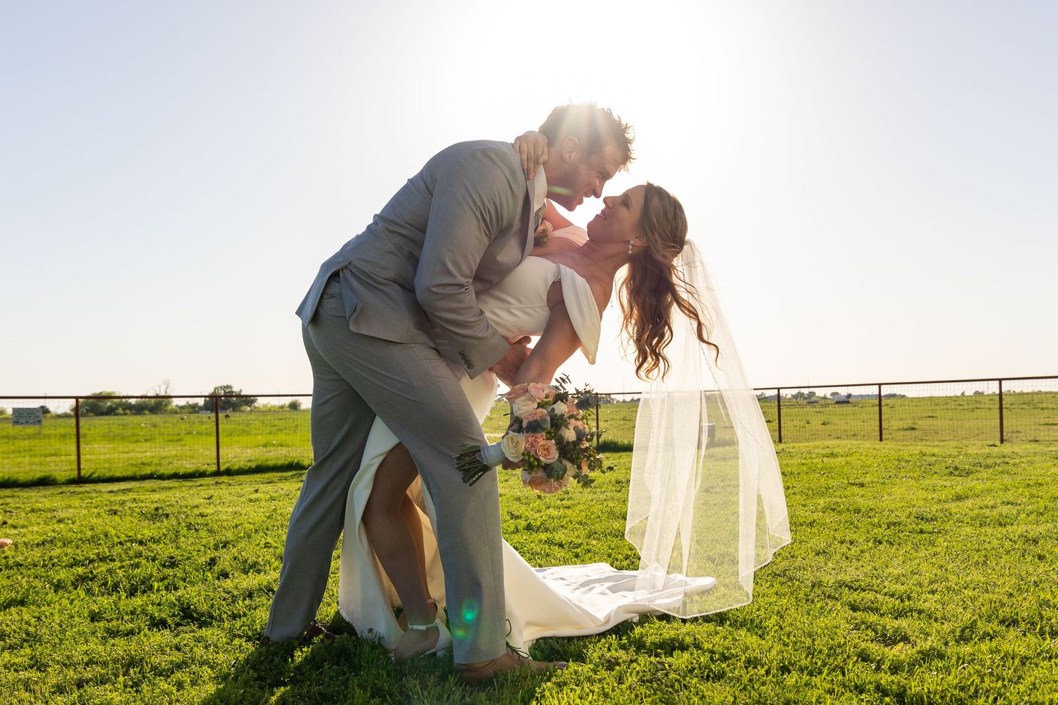 Romantic sunset wedding photos in open field with dramatic lighting.