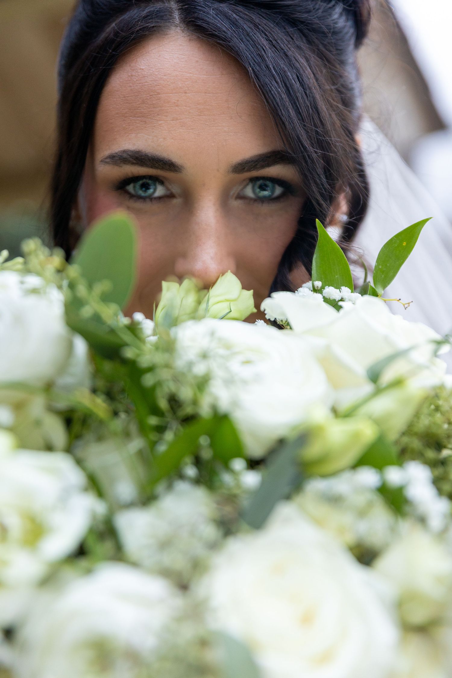 Close-up of white bridal bouquet with roses and greenery.