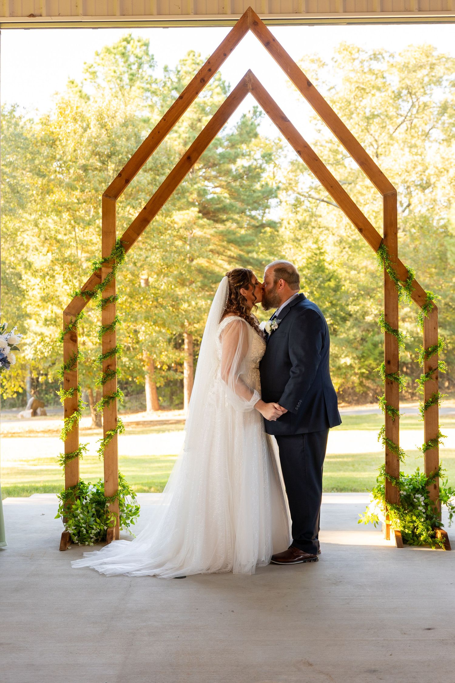 Wedding ceremony setting with wooden arch decorated with greenery in autumn.