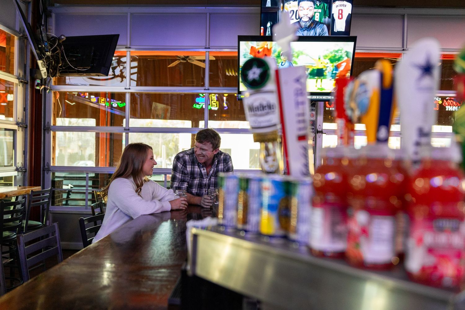 A couple sharing an intimate conversation at a casual bar counter with ambient lighting.