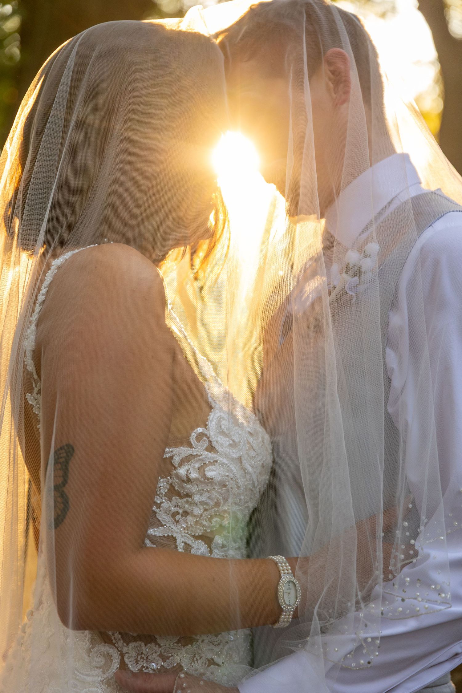 Intimate wedding portraits with sunlight streaming through delicate veil details.