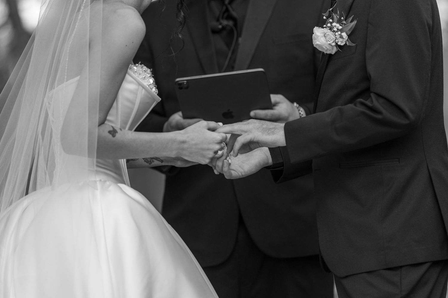 Wedding ceremony moment with couple exchanging rings under veil.