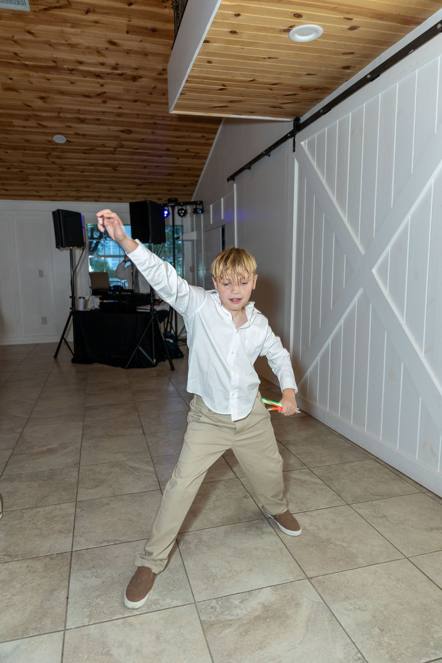 Person in white shirt and khakis dancing energetically on indoor wooden floor.
