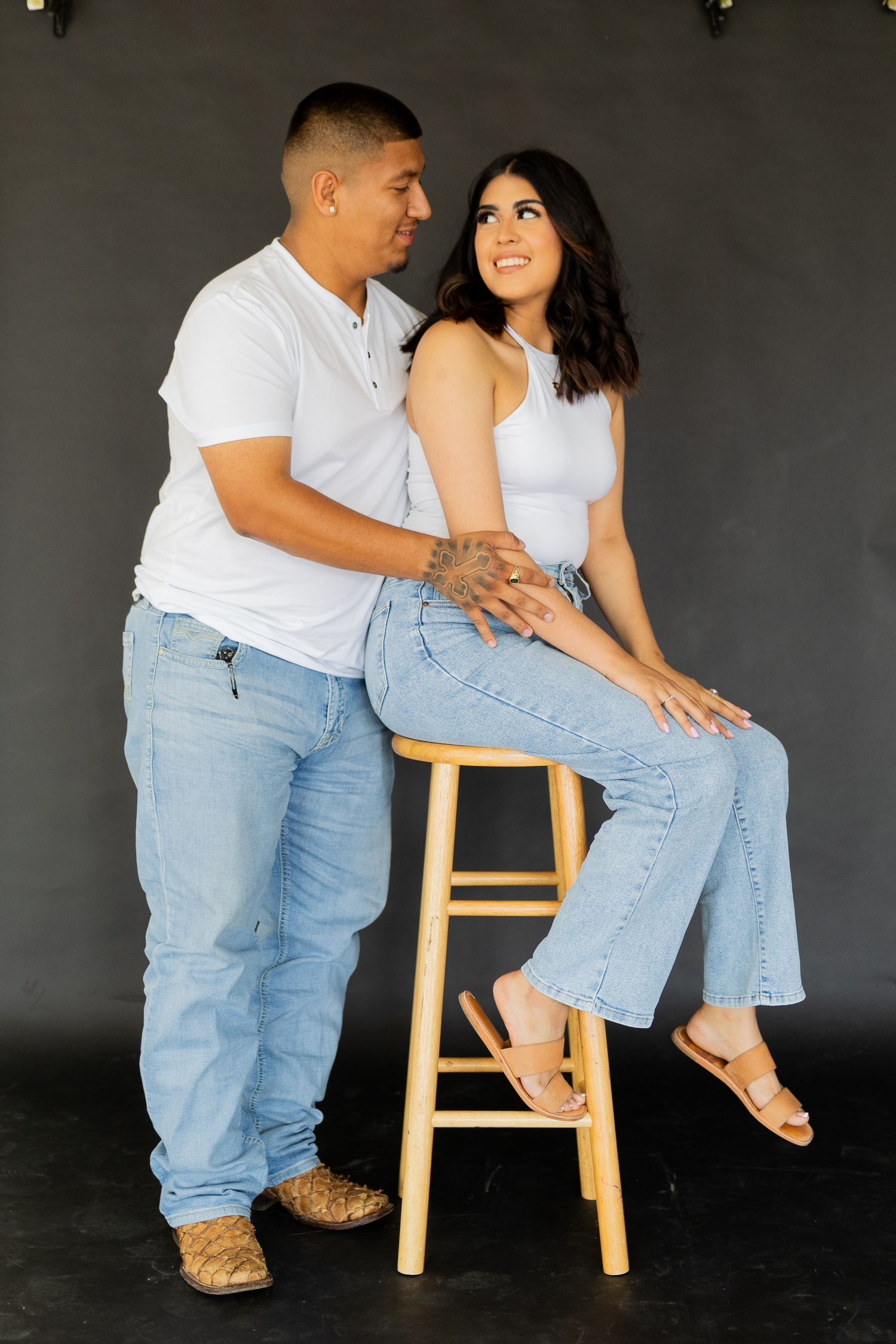 Casual family portrait series with wooden stool against dark background.