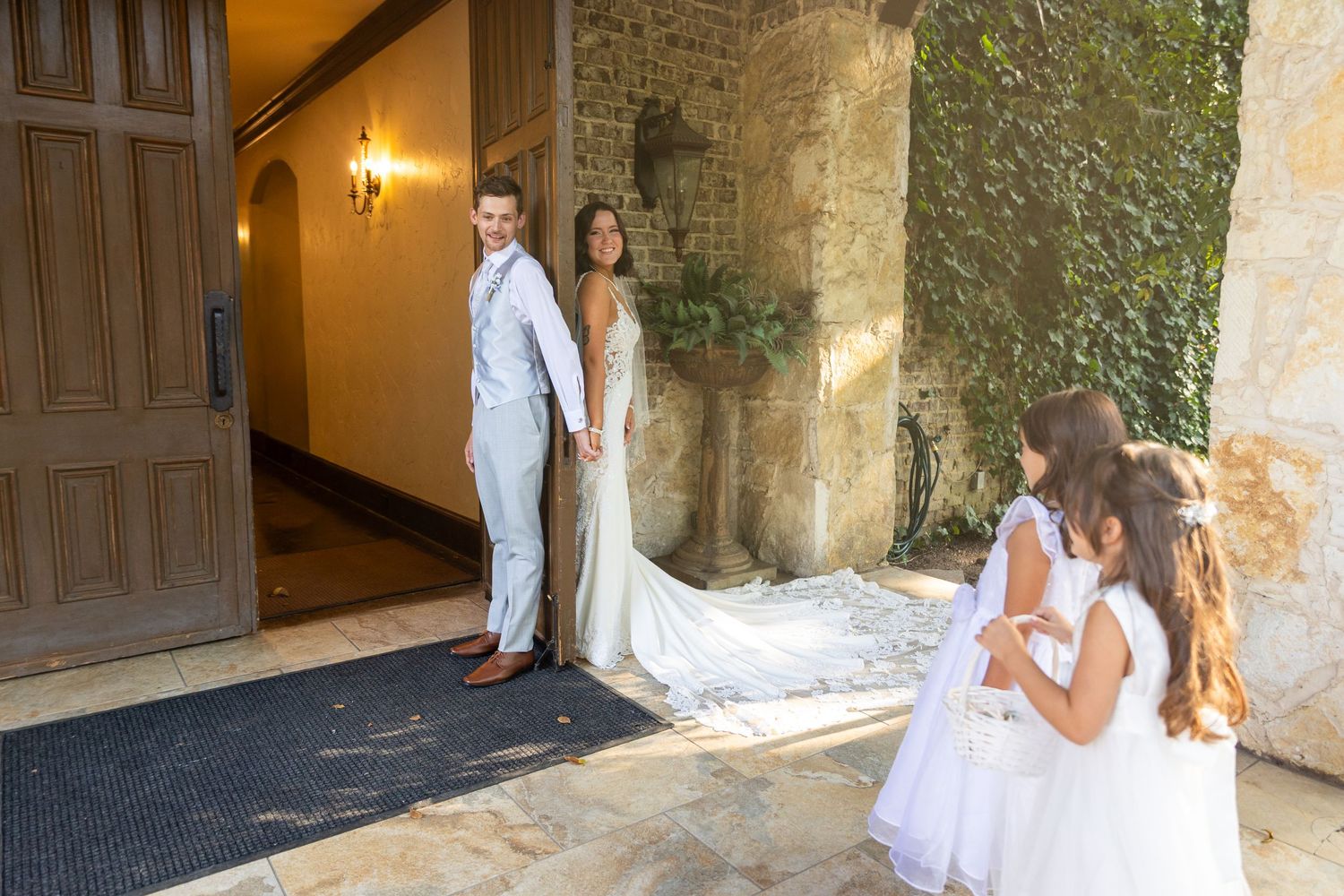 Wedding couple poses against rustic stone wall in romantic setting.