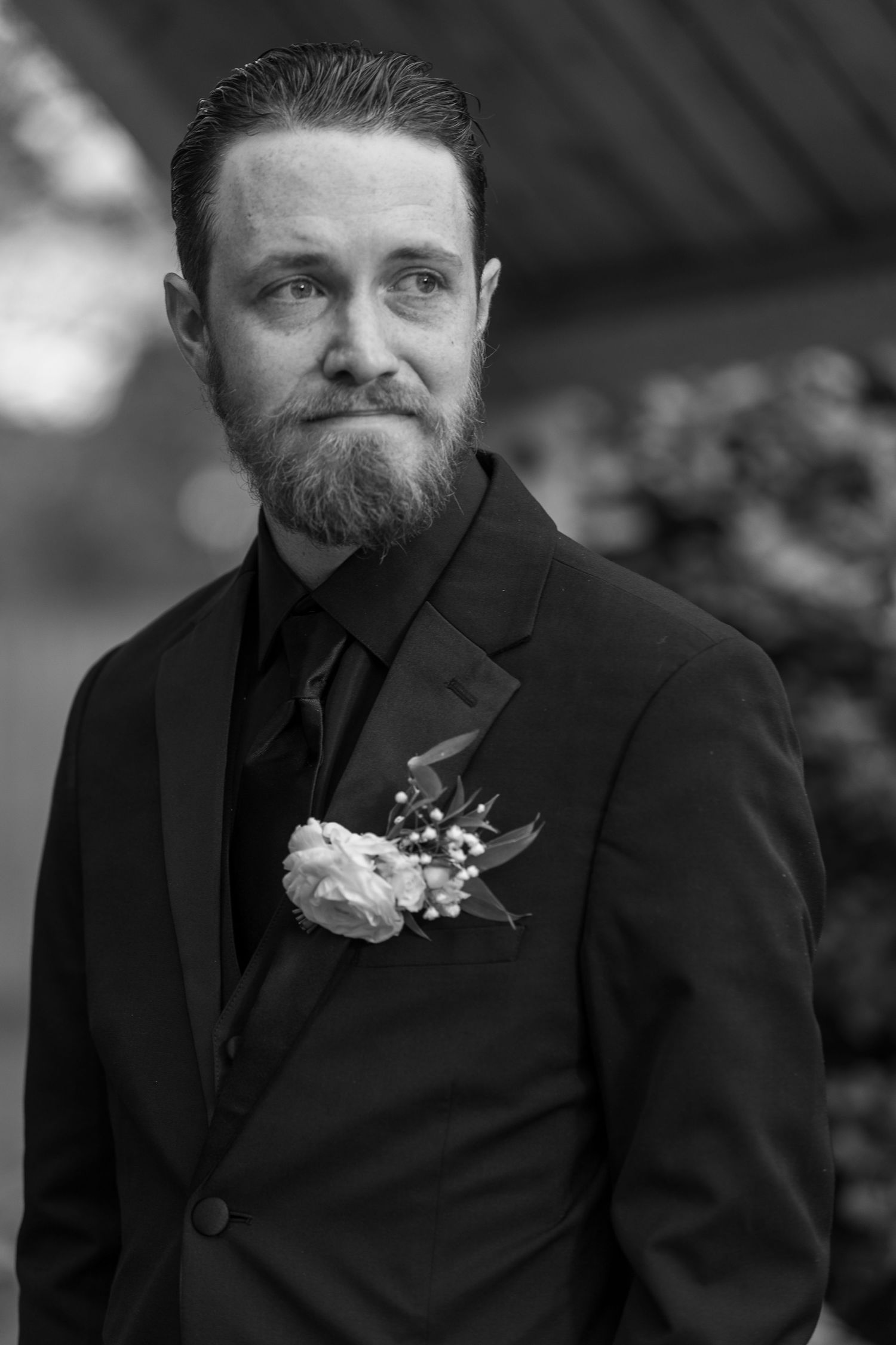 Black and white portrait of groom wearing formal attire with boutonniere.