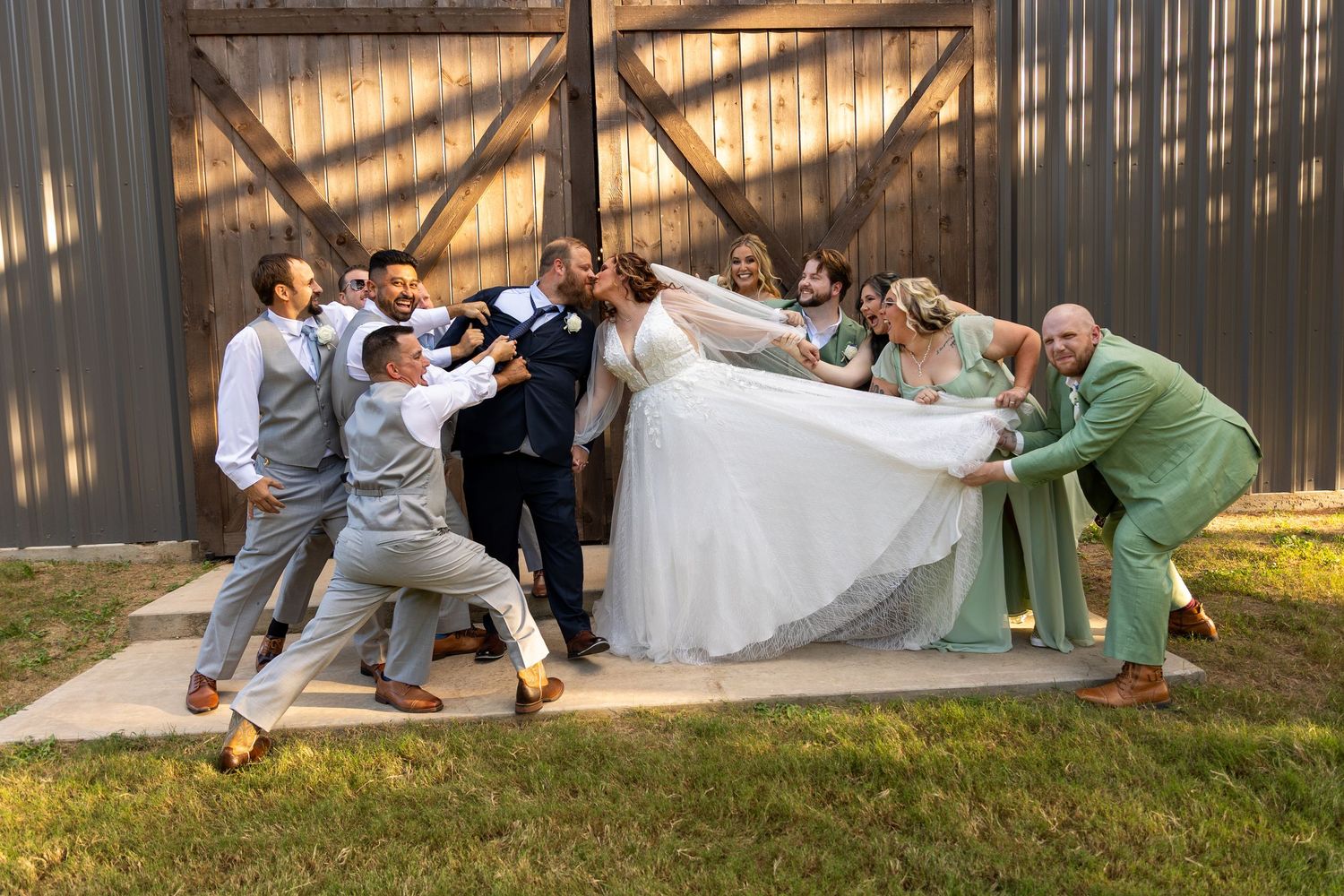 Wedding party poses playfully lying on grass for creative photo.