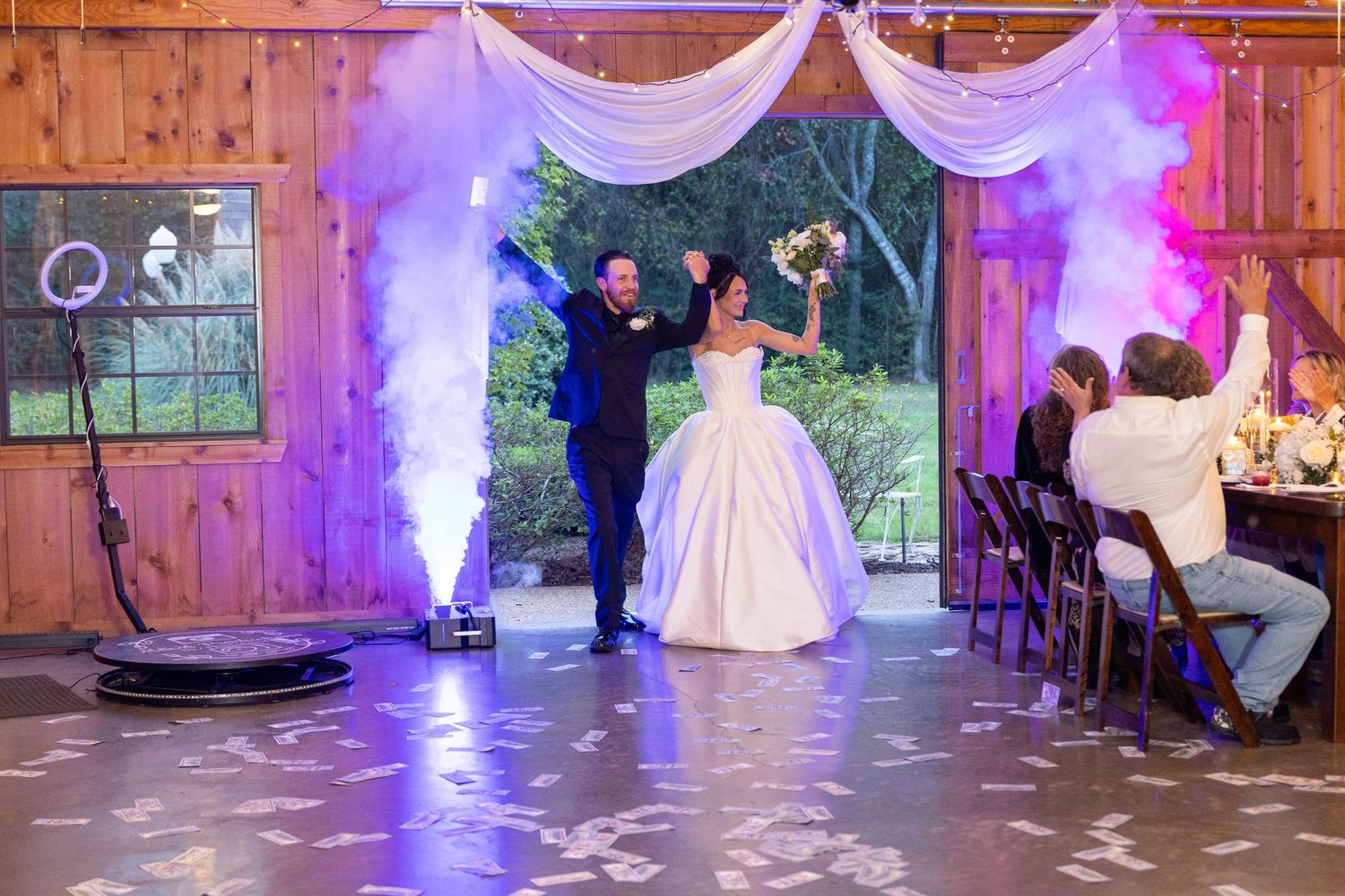 Wedding reception venue decorated with purple lighting and white fabric draping.