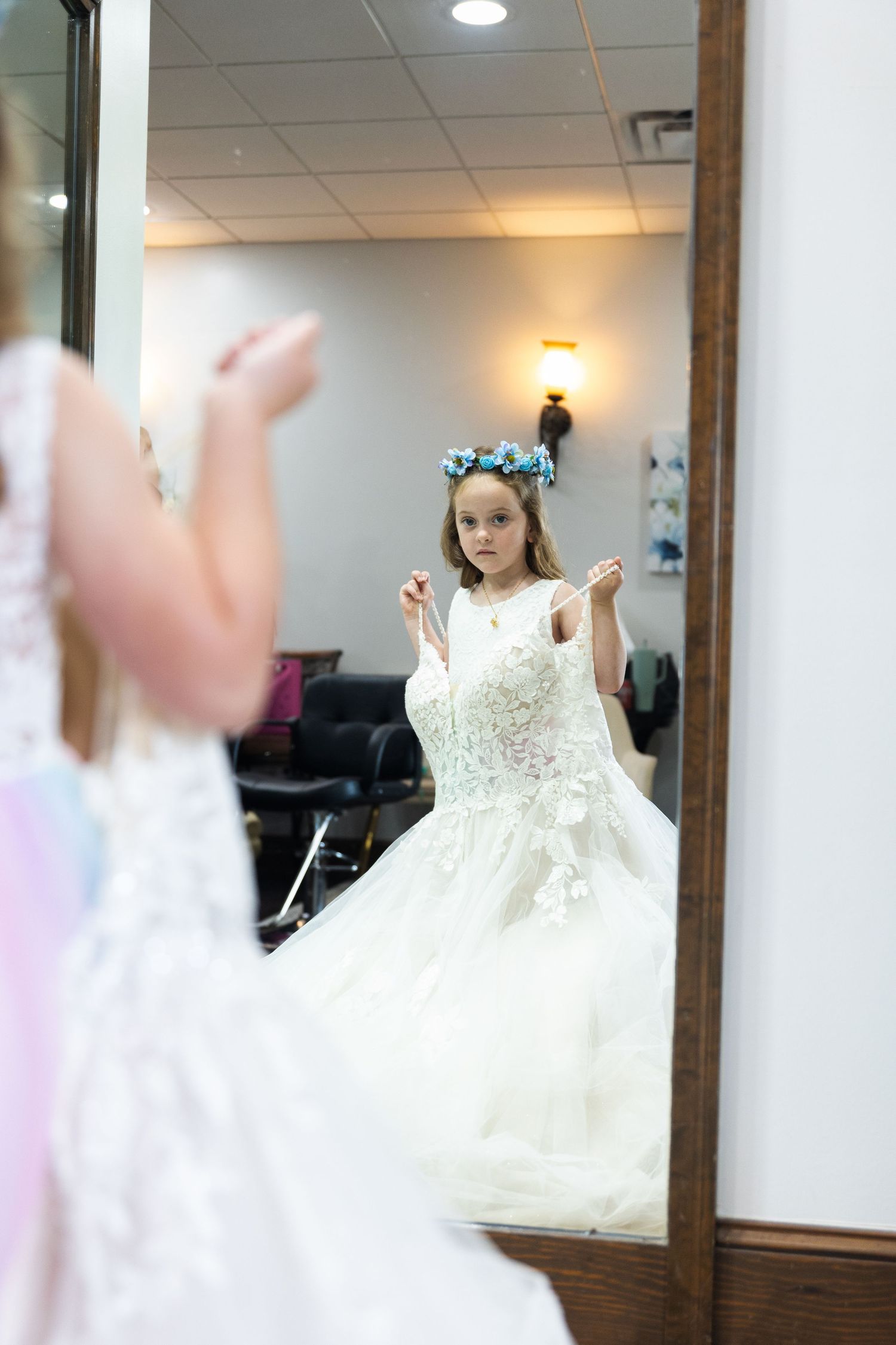 A white wedding dress twirls in motion against a mirrored wall in a bridal boutique.
