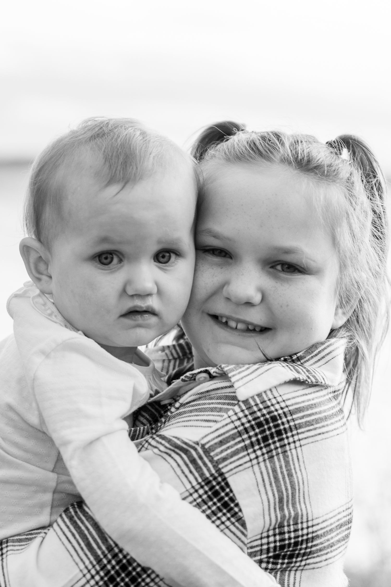 Black and white close-up portraits showing tender moments between children.
