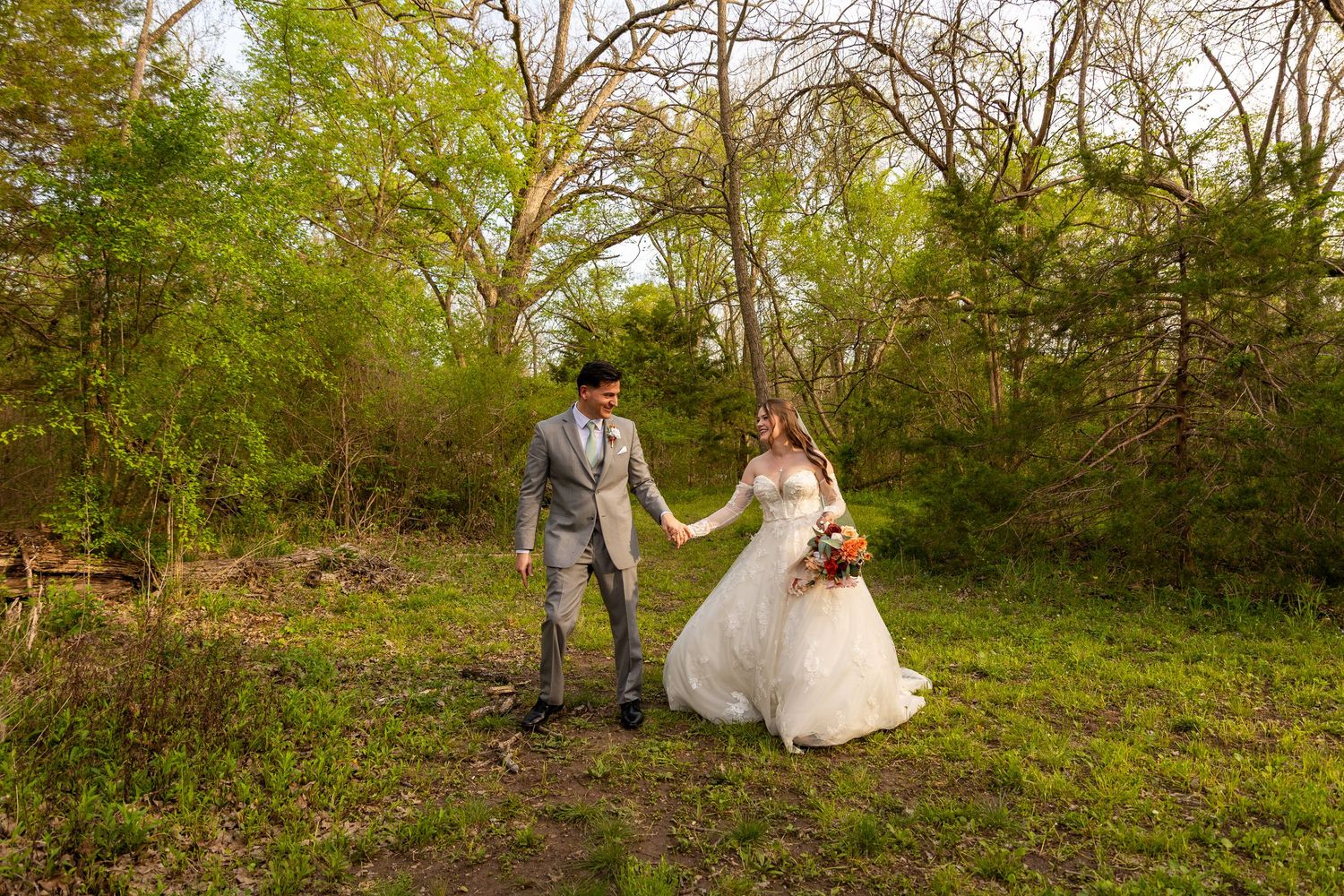 Newlyweds walking together through a scenic autumn forest path.