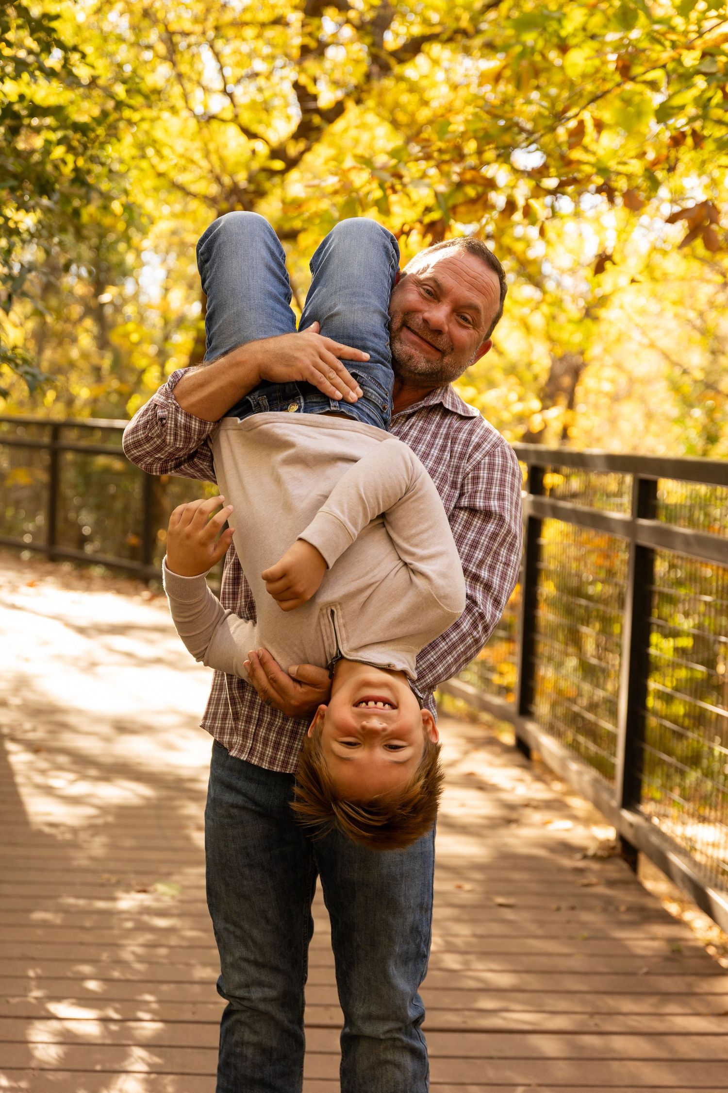 Playful family photos showing fun interactions on wooden walkway during golden hour.