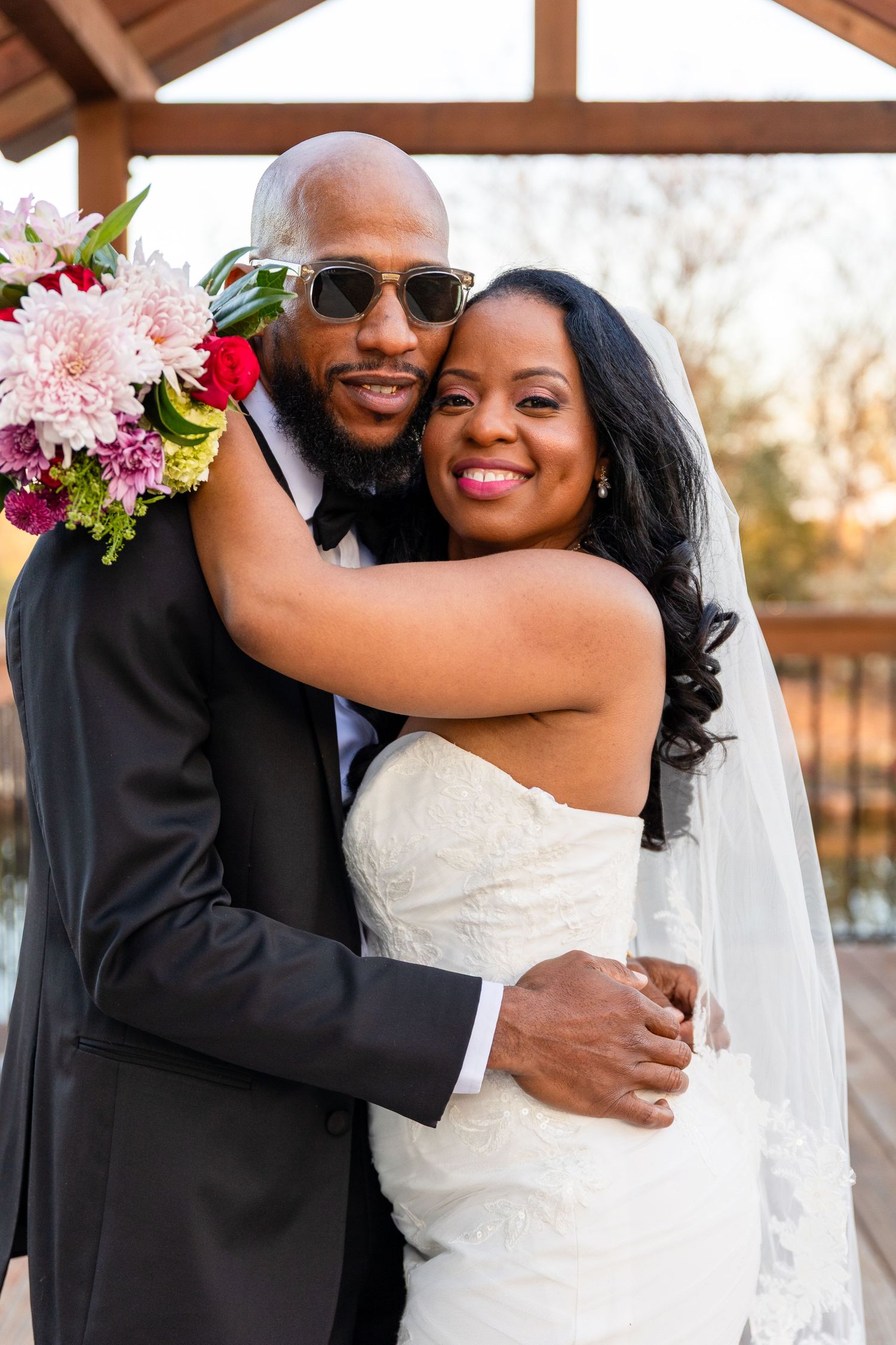 Joyful wedding portraits under wooden pergola with floral decorations.