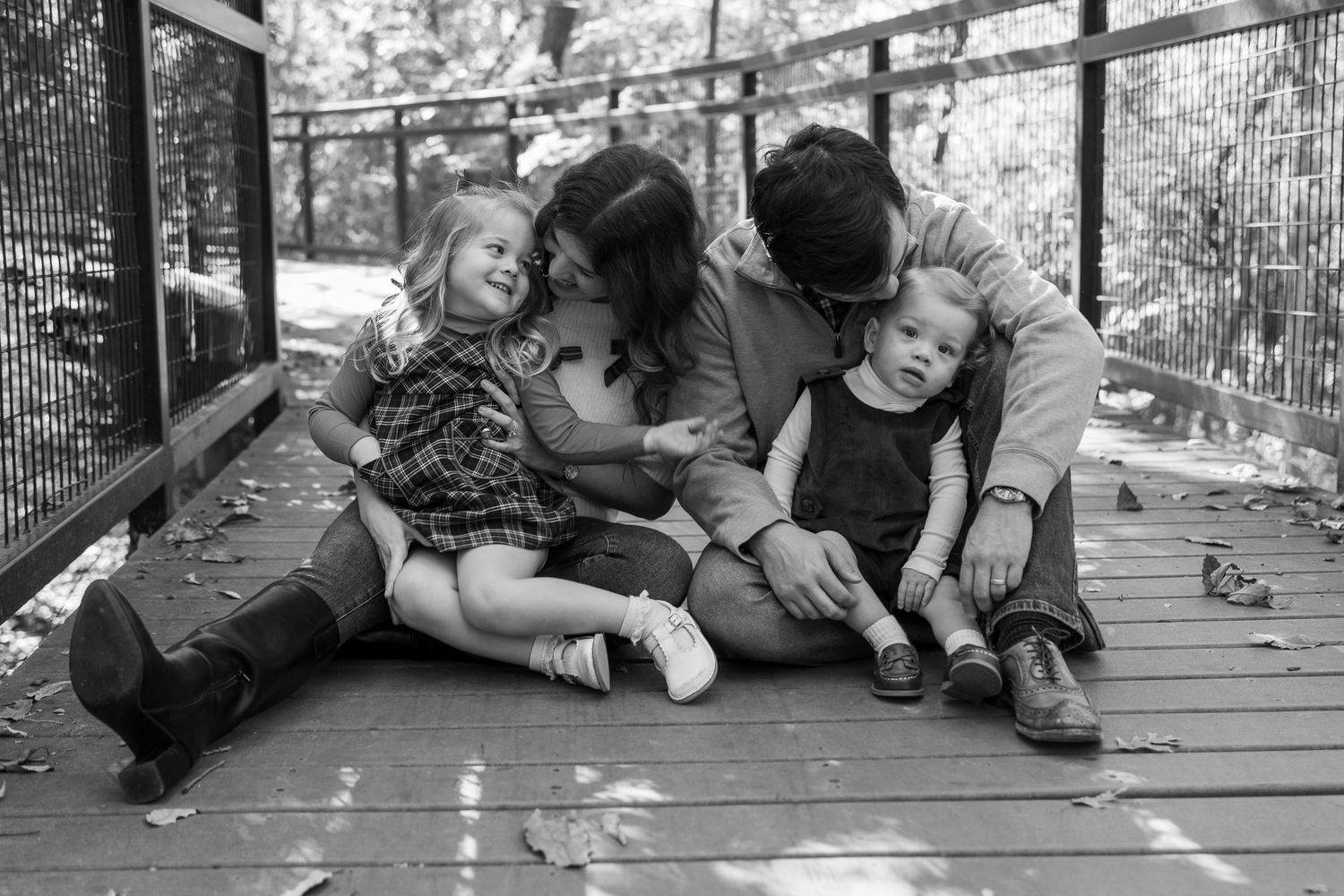 Black and white candid family photo showing playful interaction on wooden deck.
