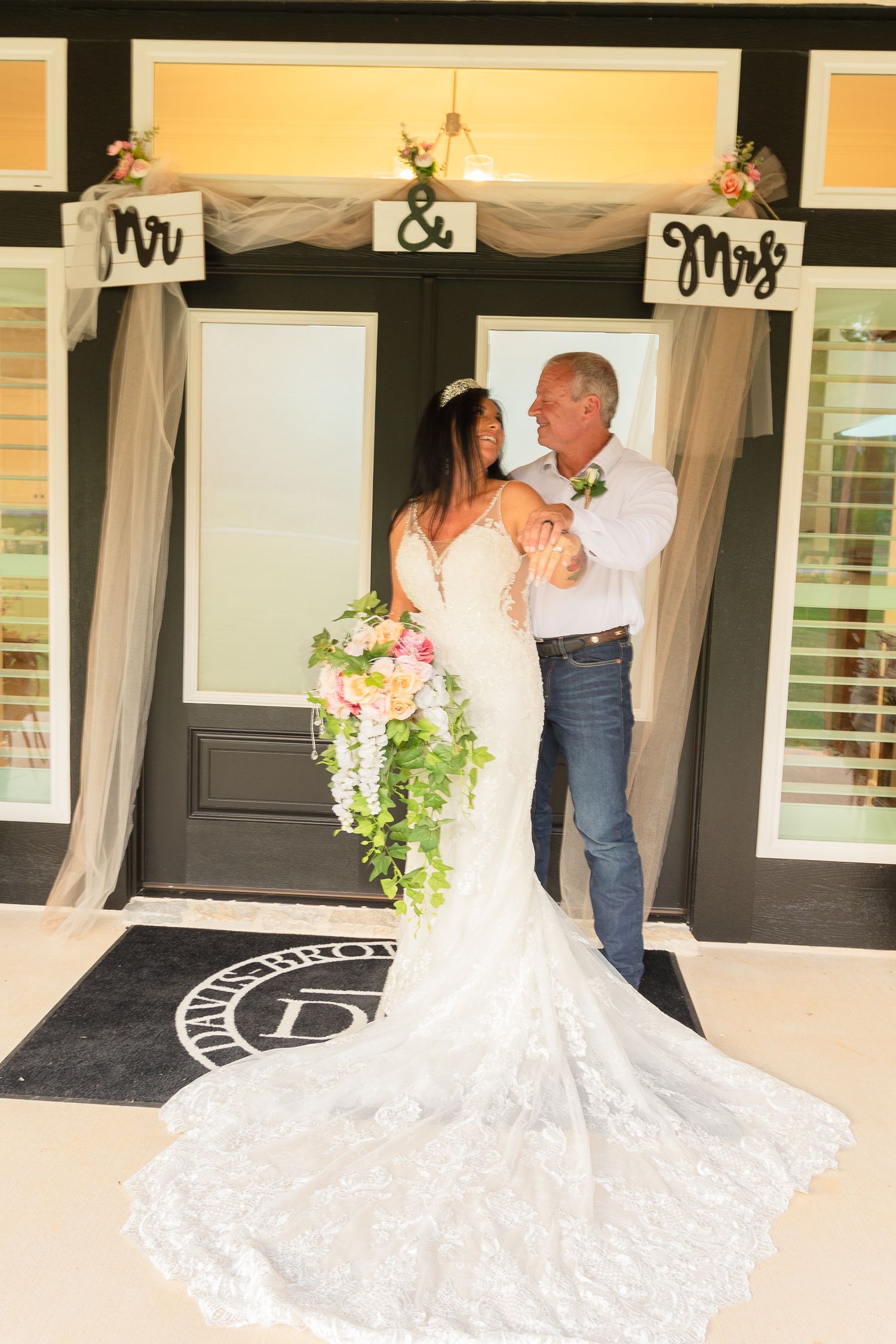 Beautiful white wedding dress with train displayed on a rustic porch with decorative elements.