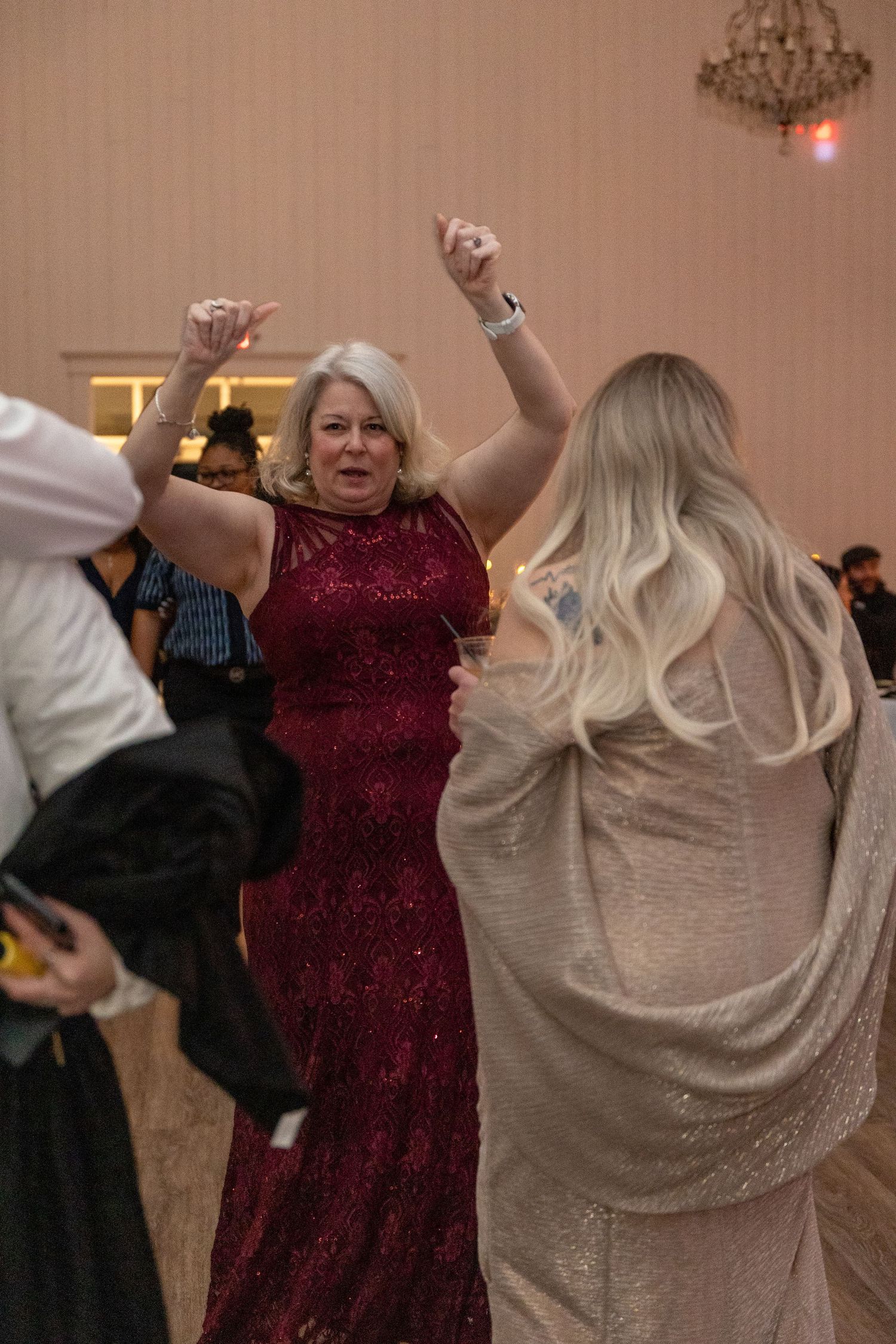 Wedding guests dancing and celebrating in formal attire at reception.