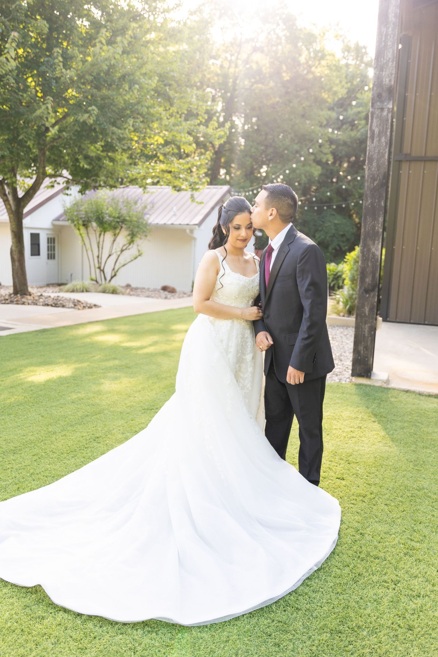 Newlyweds share intimate moments on grassy lawn during golden hour wedding photos.