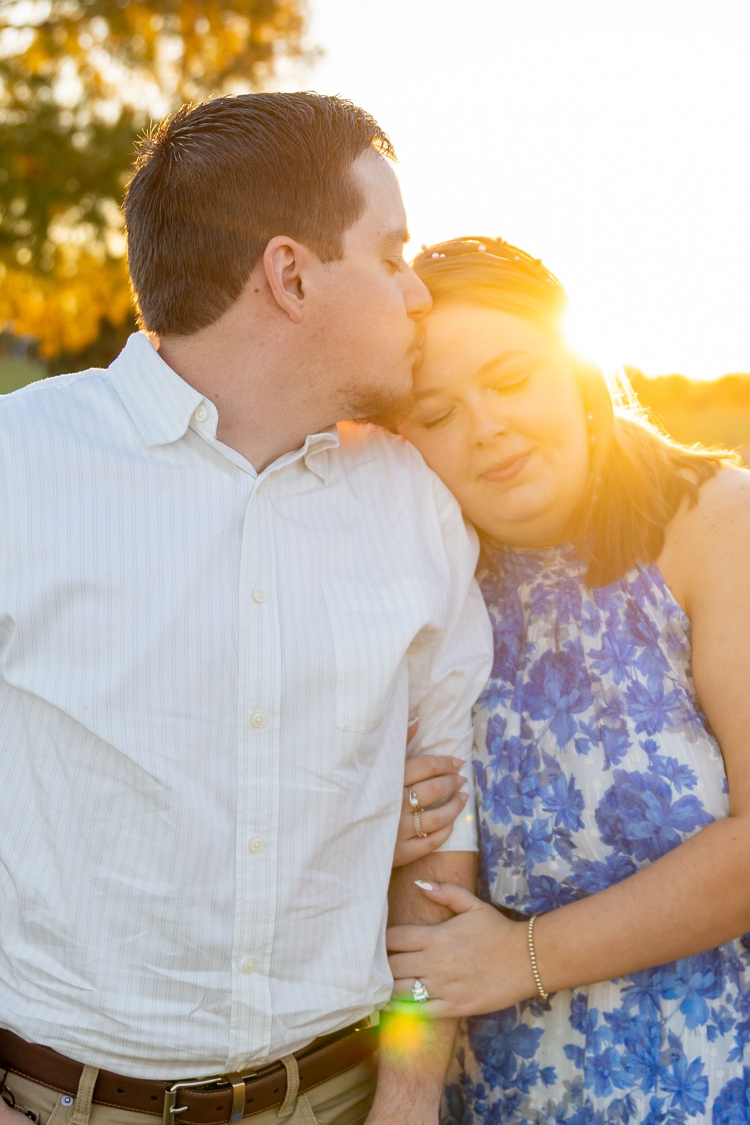 A tender sunset moment between a couple in casual attire with golden light streaming through.