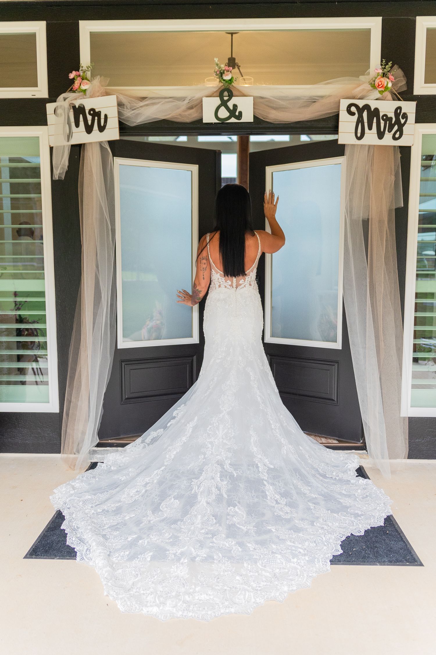 A stunning white lace wedding dress with a dramatic cathedral train displayed on a porch.
