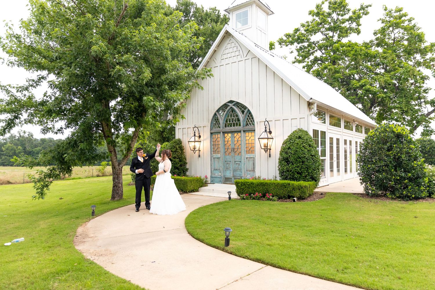 White chapel wedding venue set on rolling green hills with landscaped grounds.