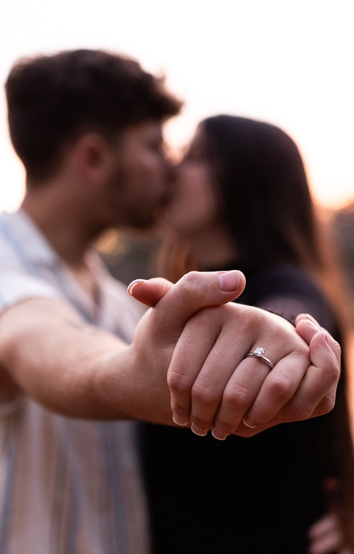 Close-up shots of hands displaying an engagement ring during a sunset photoshoot.