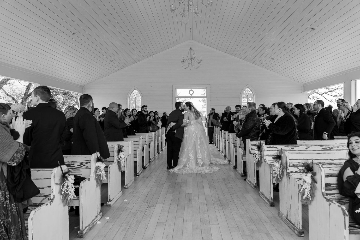 Black and white panoramic view of a chapel interior during a wedding ceremony.