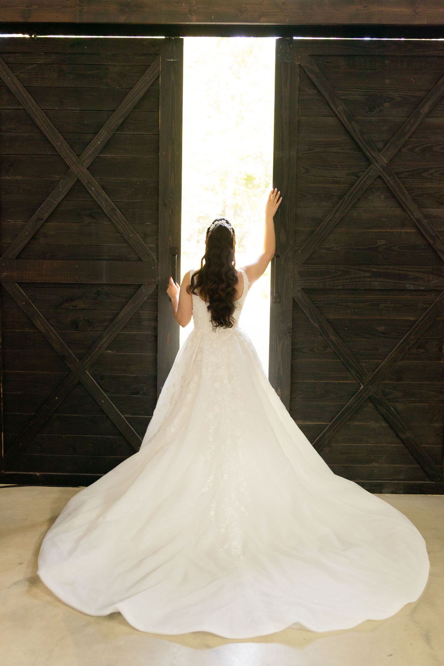 Wedding dress train spreads beautifully across dark wooden floor in dramatic twirling sequence.