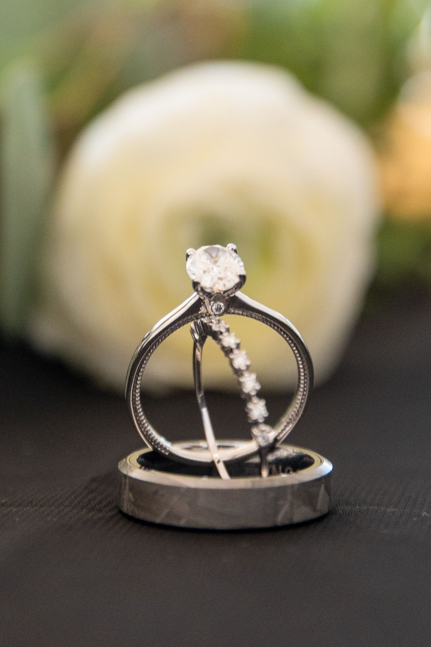 Close-up of delicate wedding rings with diamond details on dark background.