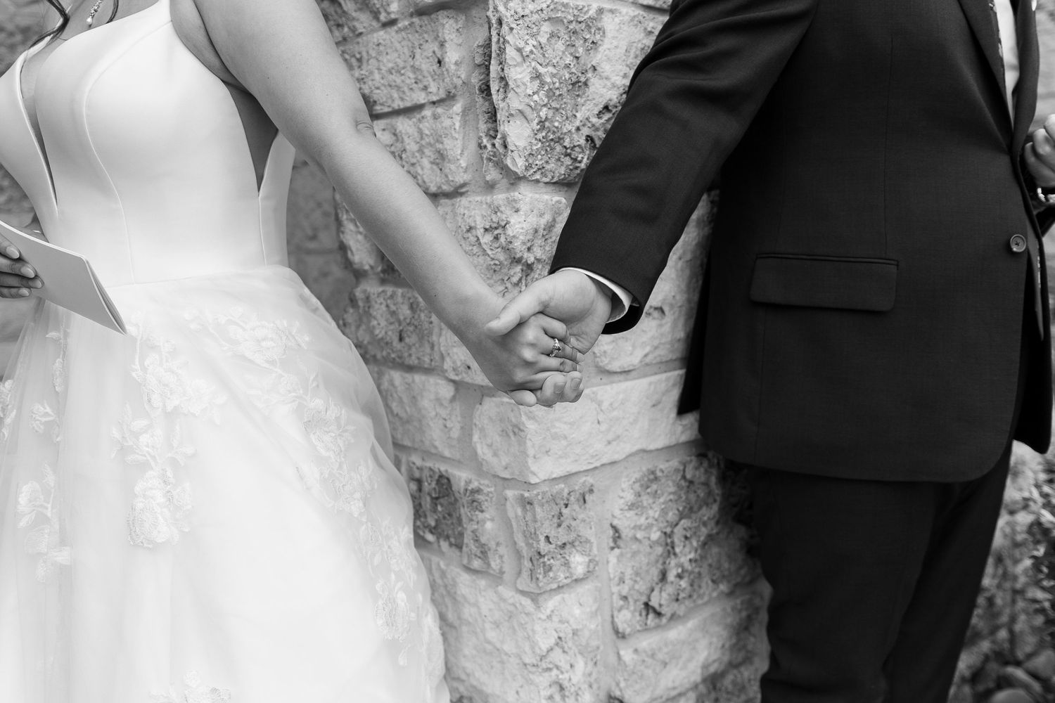 Black and white photos of romantic wedding moments against a stone wall.