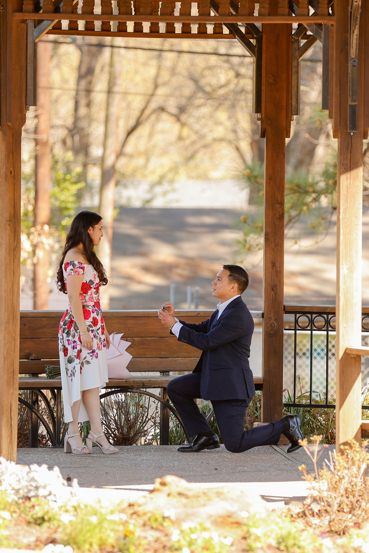 A proposal moment captured in a wooden gazebo during autumn.