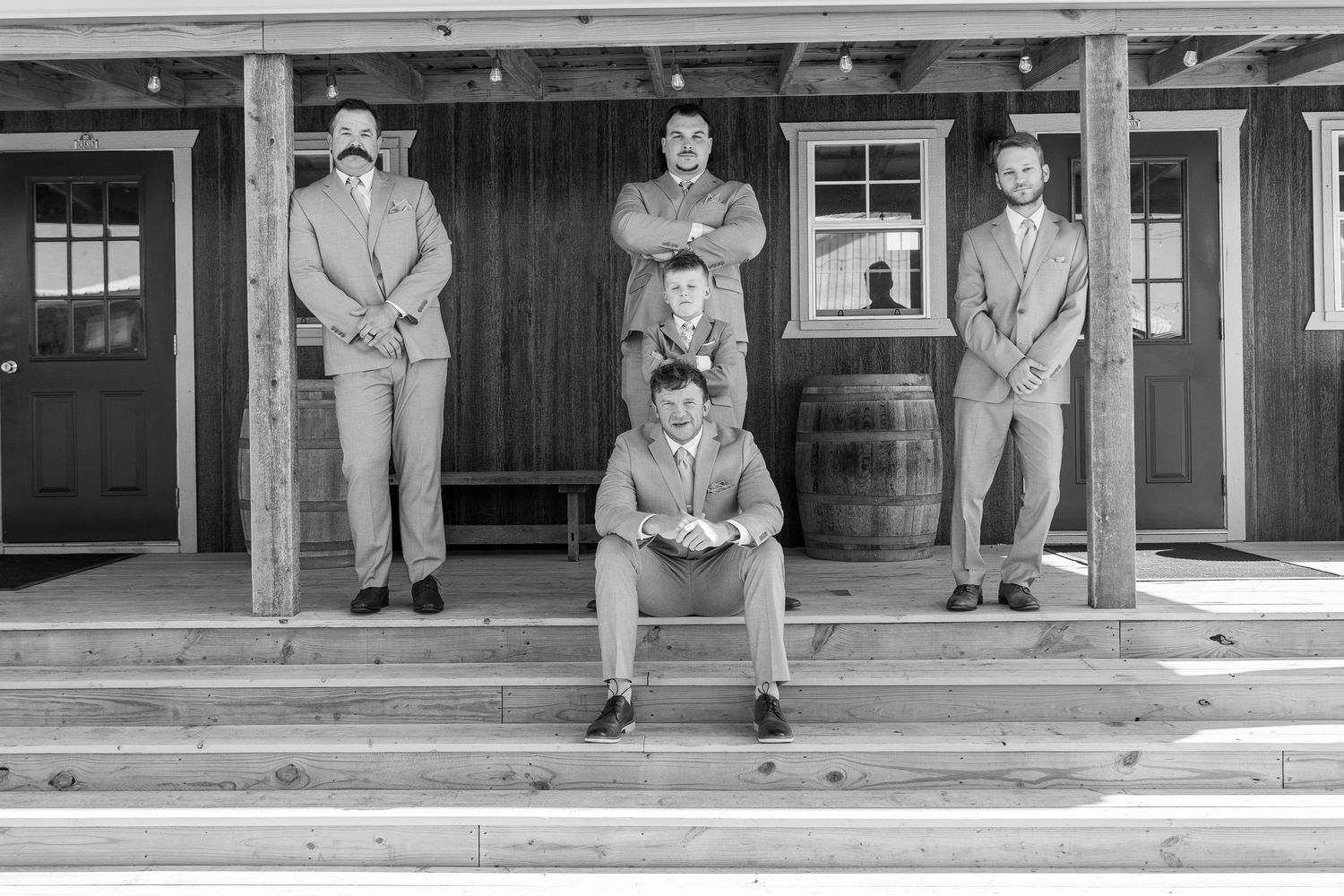 Black and white photo of wedding party lined up on rustic wooden porch.