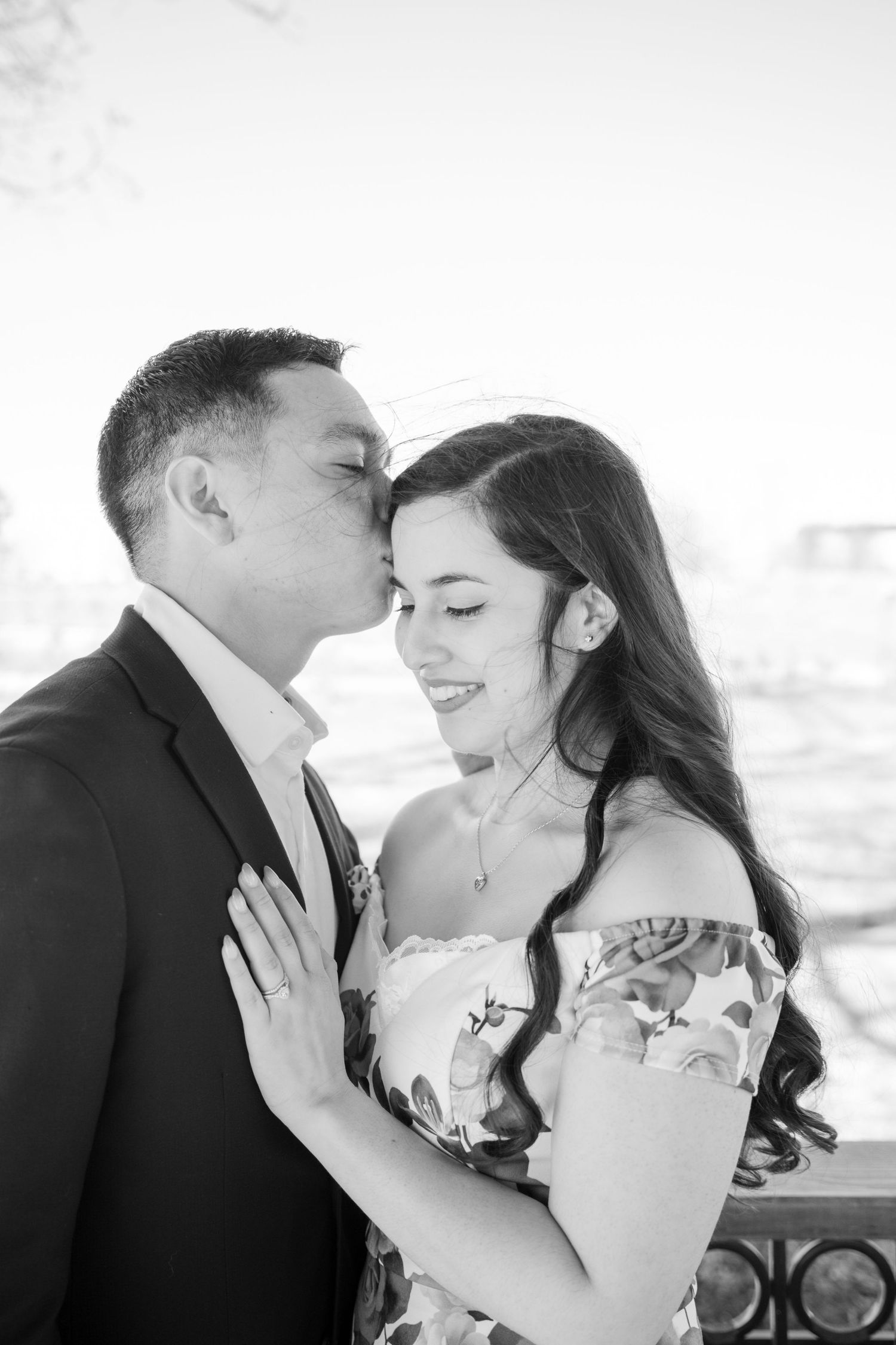 A black and white intimate portrait of a couple sharing a tender moment outdoors.