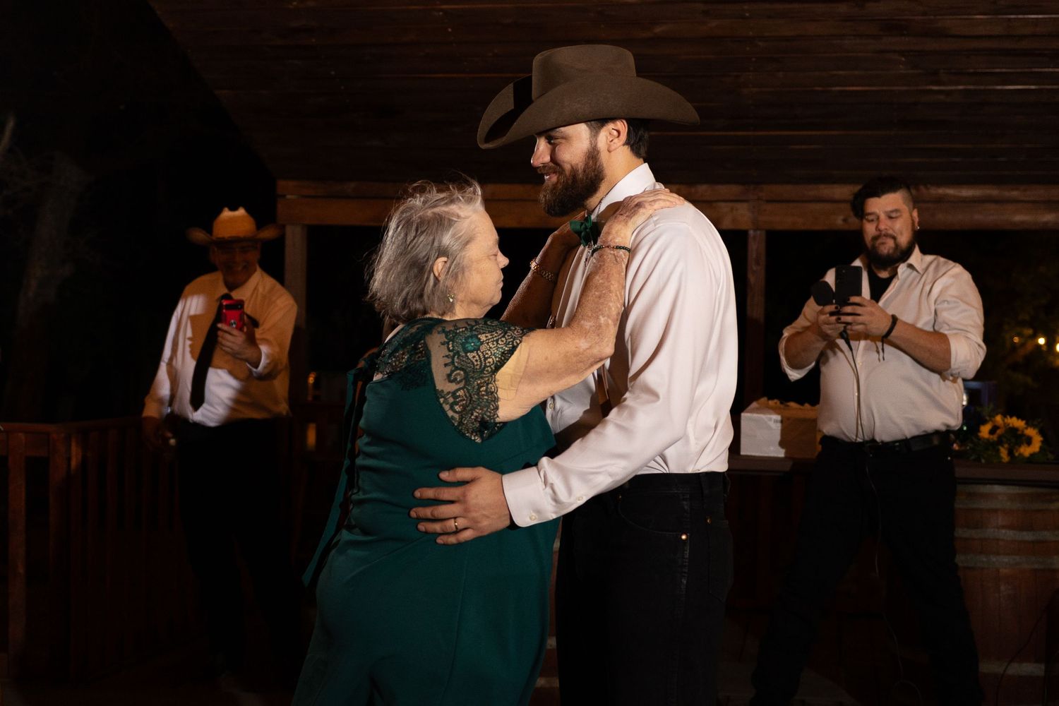 A couple shares an intimate dance in a rustic barn setting with musicians in the background.