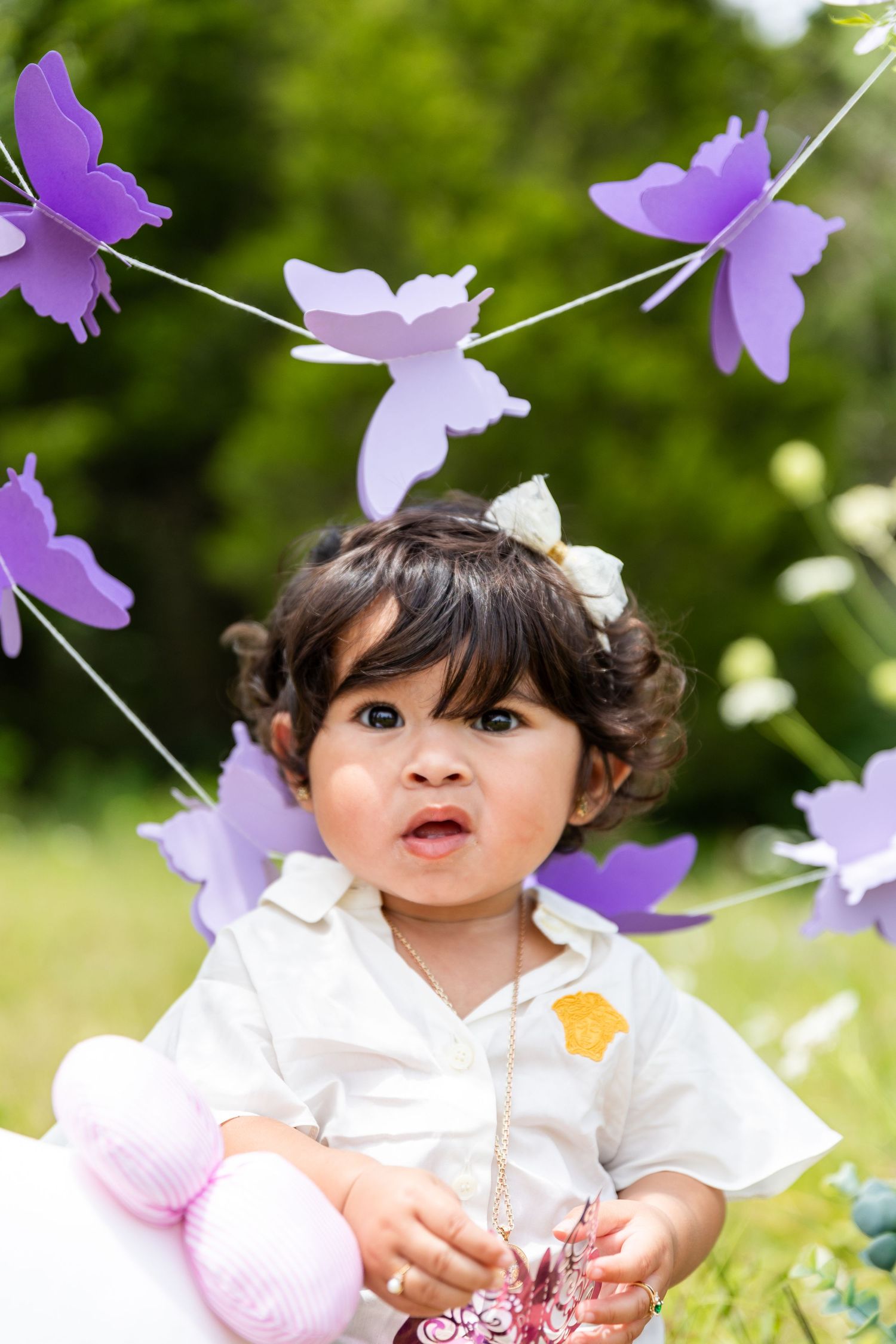 Whimsical outdoor photo setup with purple butterflies and floral decorations.