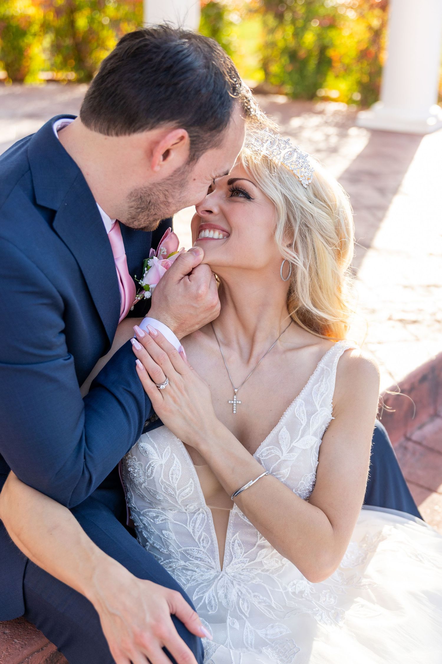 Romantic wedding couple sharing intimate moments on a sunlit porch.