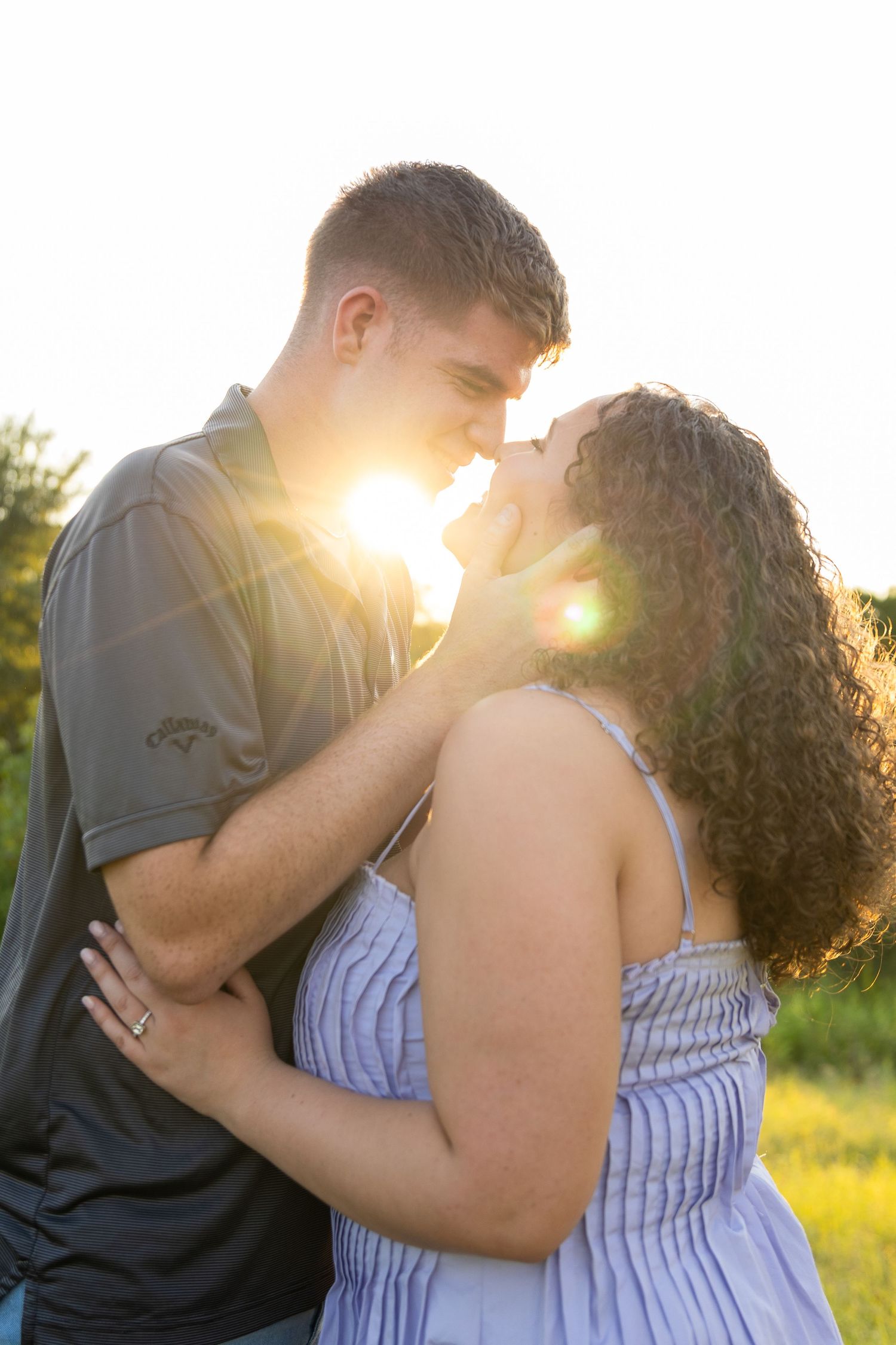 Romantic couple embracing in a sunlit field during golden hour.