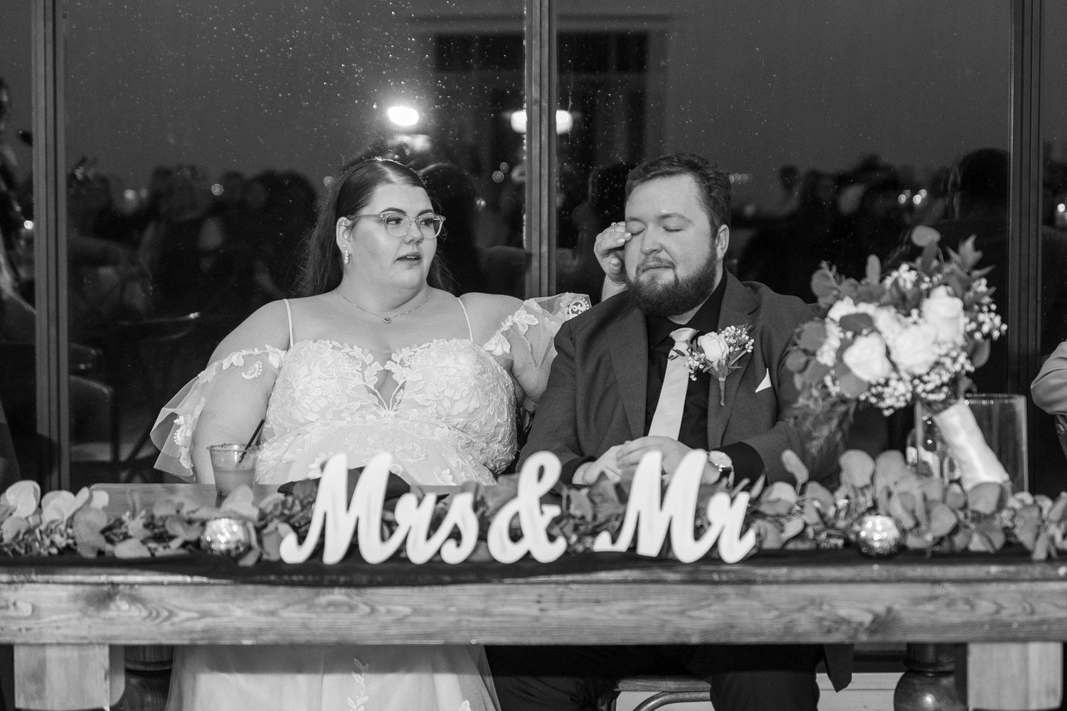 A romantic wedding reception table decorated with white flowers and a 'Mr & Mrs' sign.