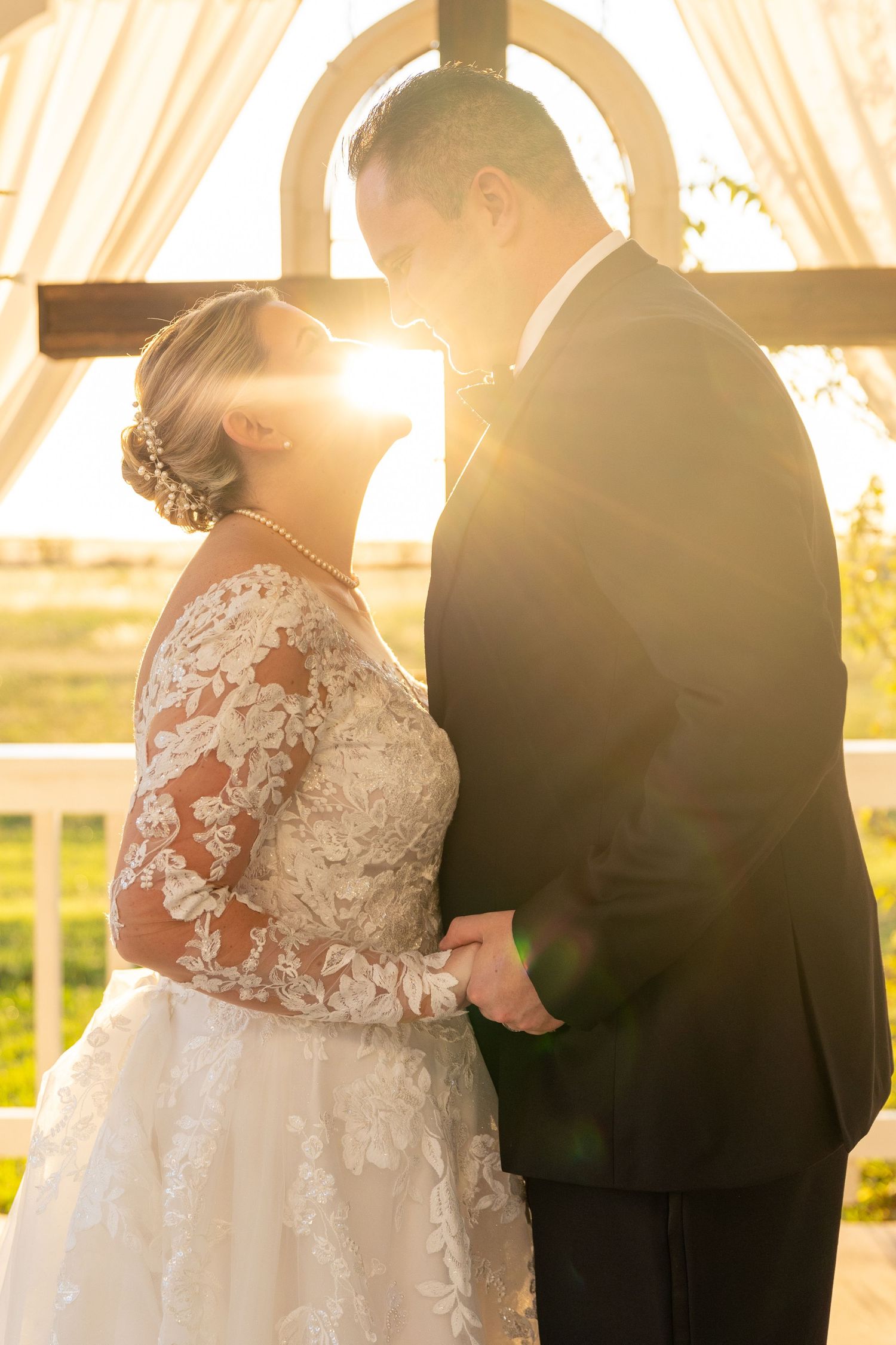 Romantic sunset wedding ceremony silhouette under outdoor gazebo.