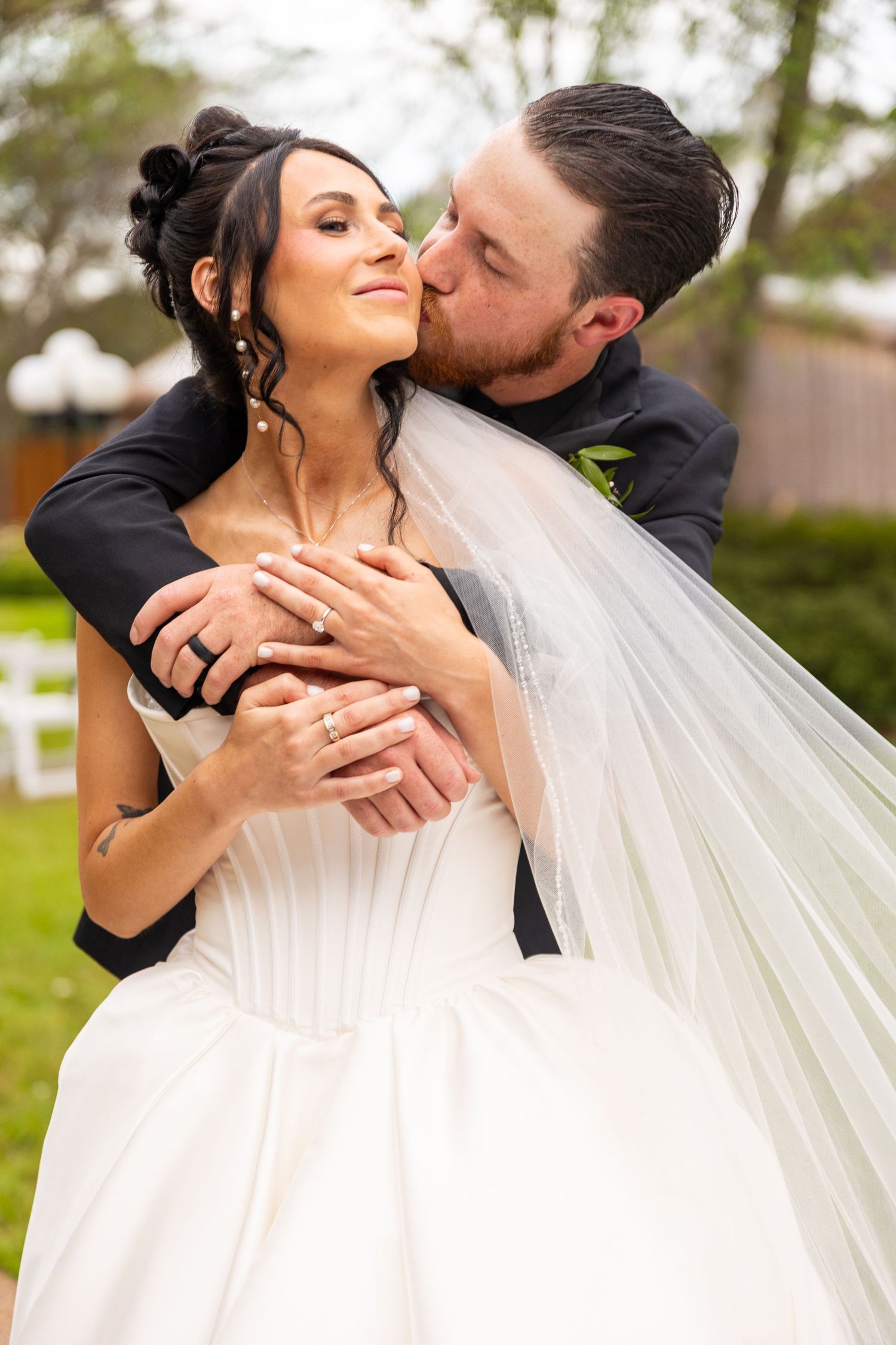 Romantic wedding couple shares intimate kisses in a series of outdoor portraits with flowing white veil.