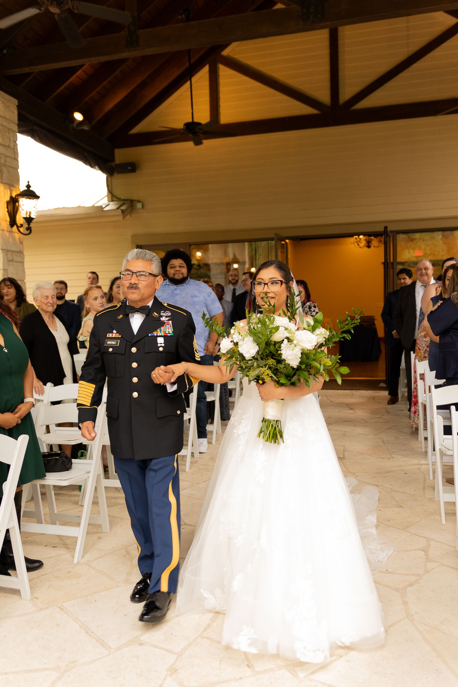 Indoor wedding ceremony venue with white chairs and floral decorations.