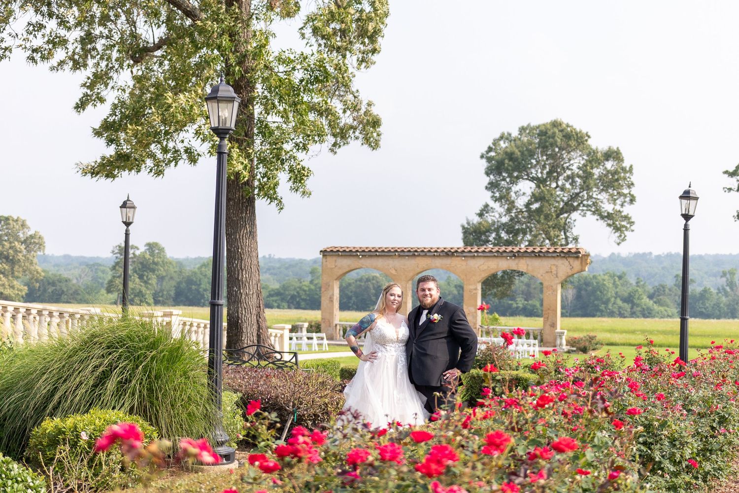 A scenic wedding venue with red roses in the foreground and stone architecture in the background.
