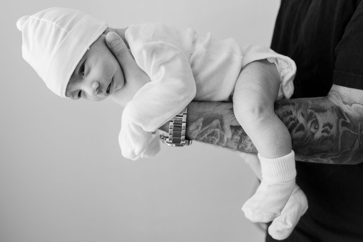 High key black and white artistic portrait of sleeping newborn on textured background.