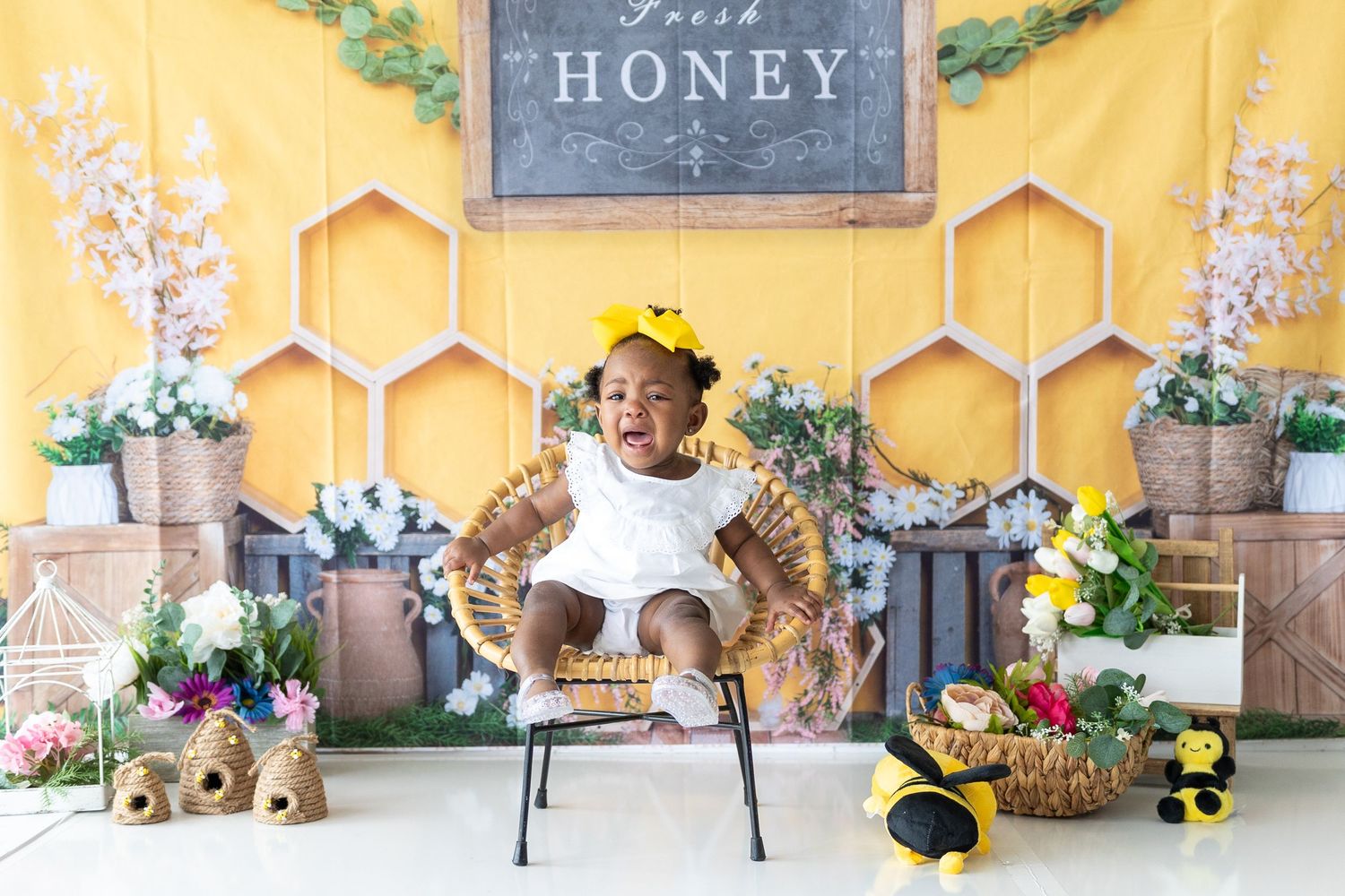 Yellow backdrop with rustic honey-themed decorations and floral arrangements for a photo session.