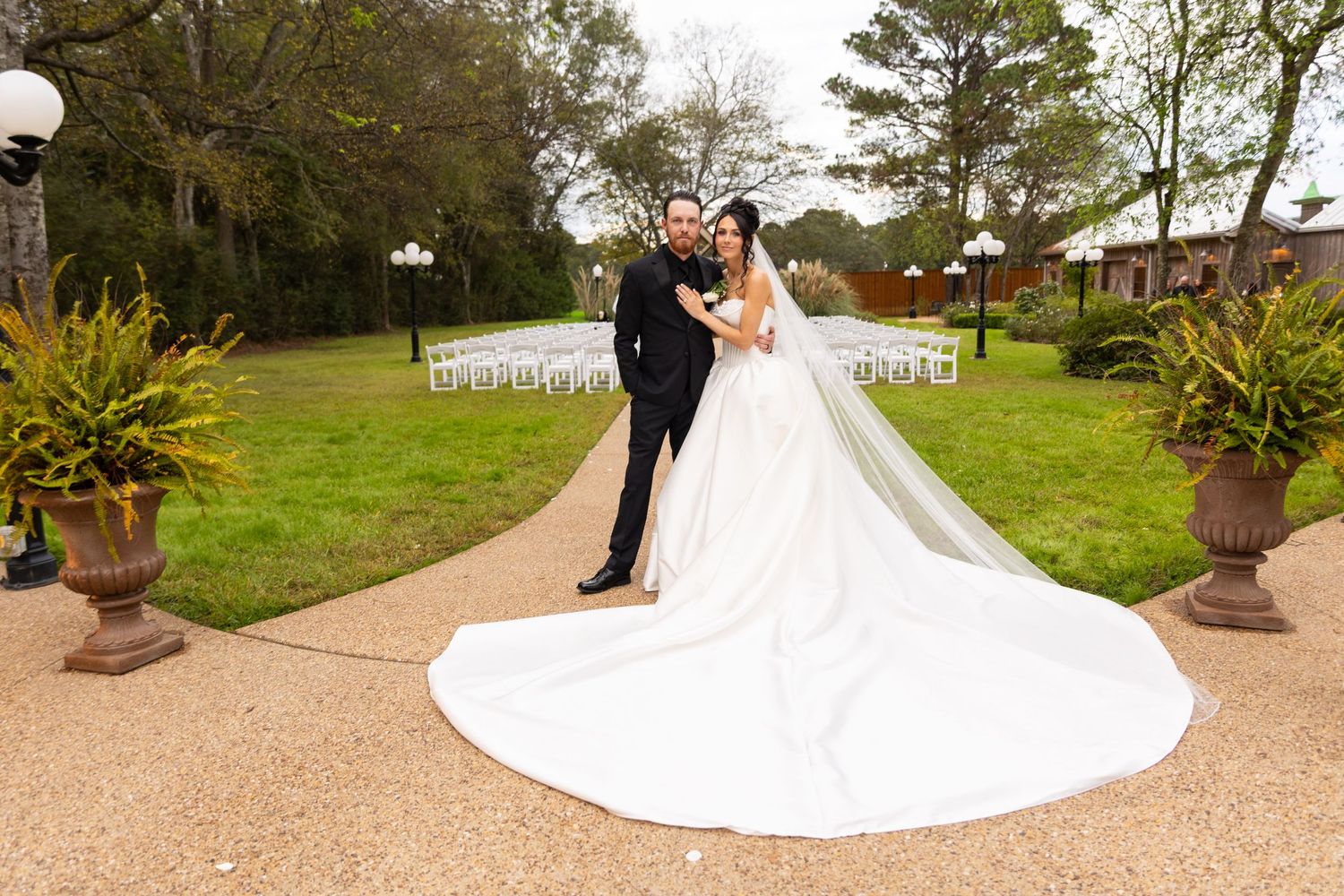 Wedding ceremony setup with white chairs and floral arrangements on a manicured lawn.