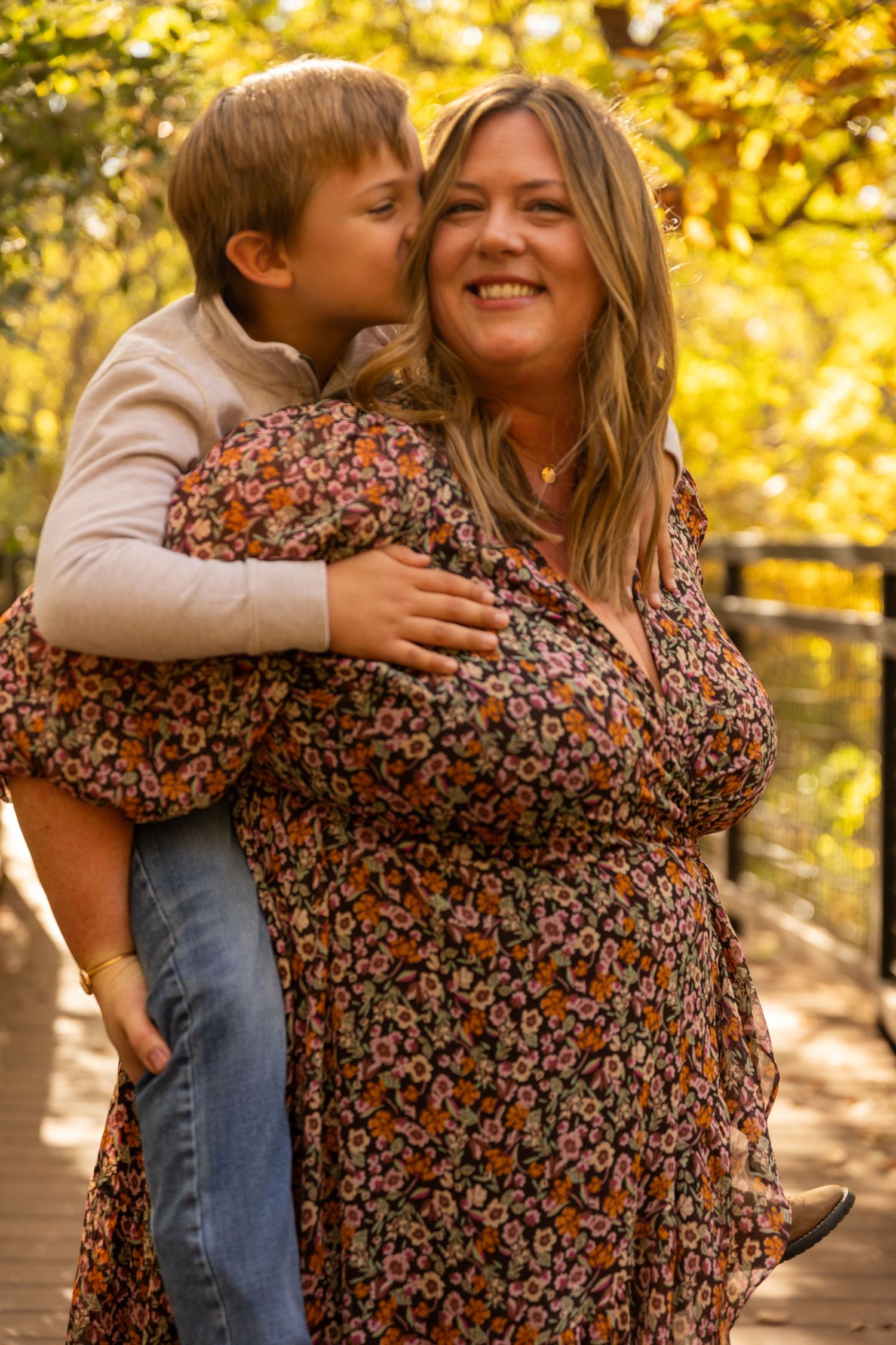 Warm autumn photoshoot showing tender family moments on wooden bridge with fall foliage.
