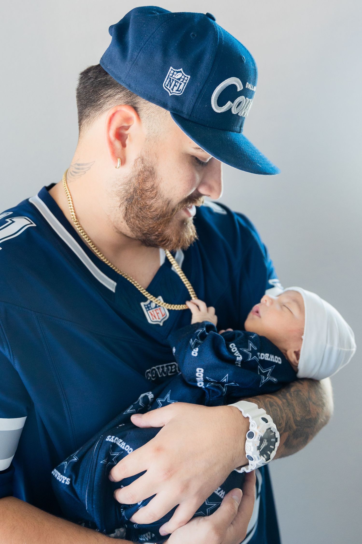 Parent wearing blue sports attire shares intimate bonding moments with newborn baby.