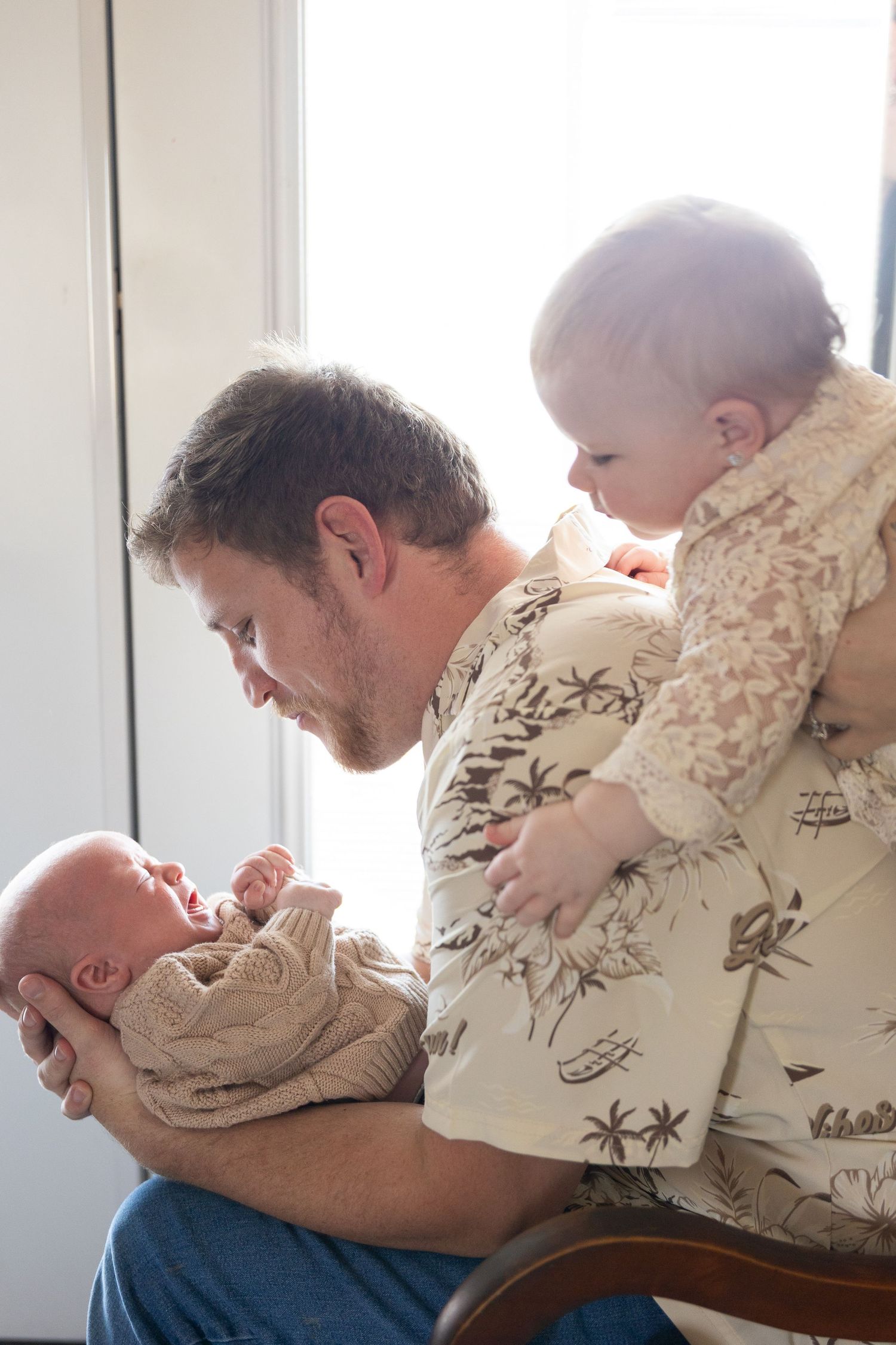 Tender moment between parent and children in soft natural window light.