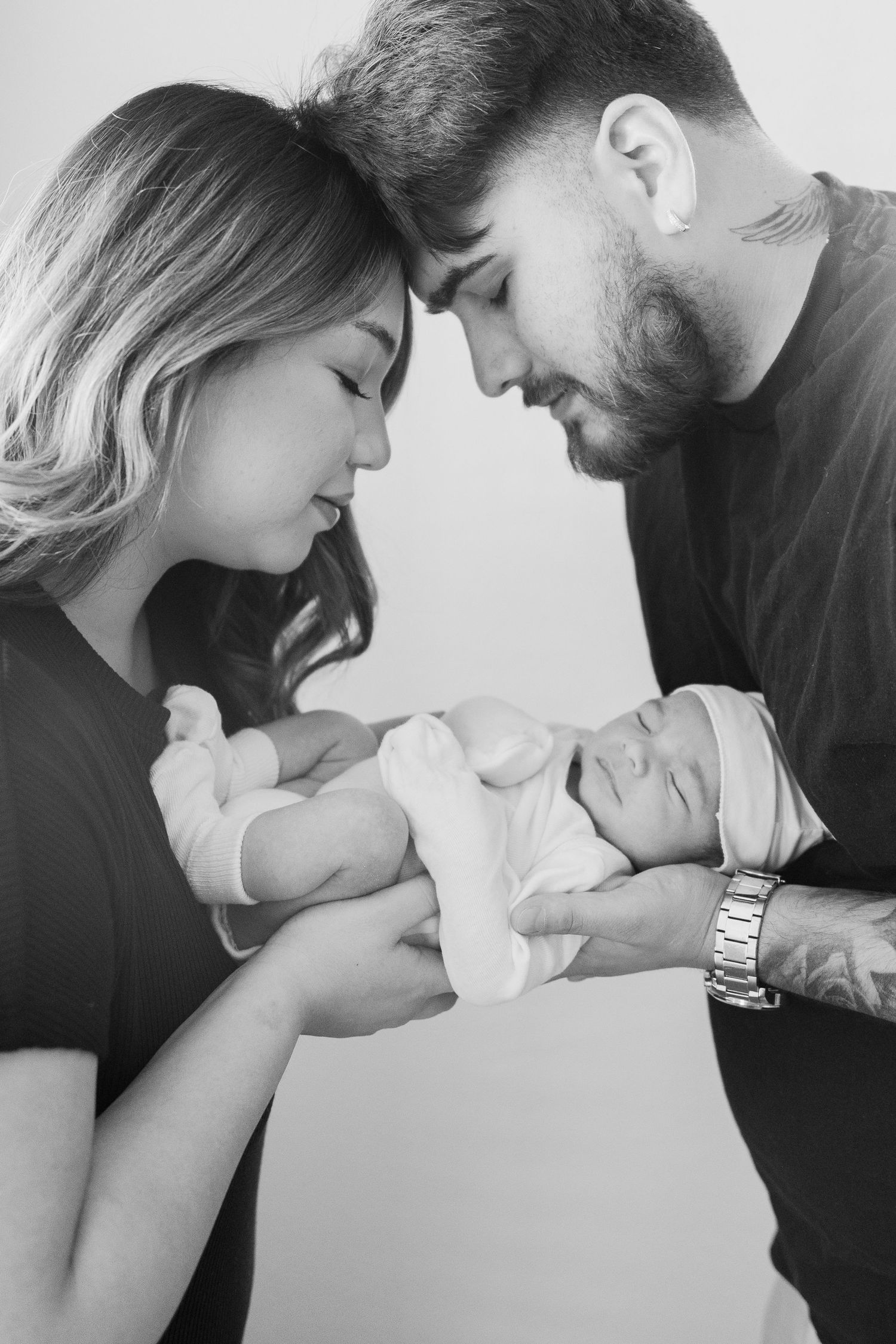 Black and white photo series showing tender moments between parents and their newborn baby.